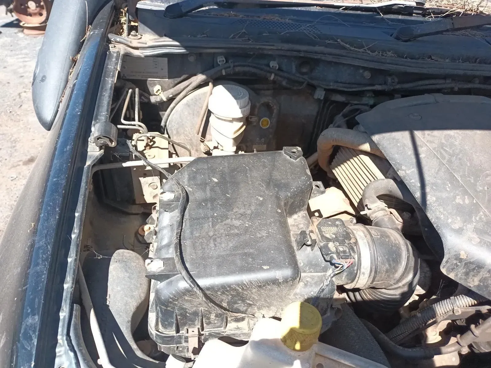 Car Engine Bay, Dusty, Black Components, White Fluid Reservoir, Outdoors — South West 4WD Wreckers In Brisbane, QLD