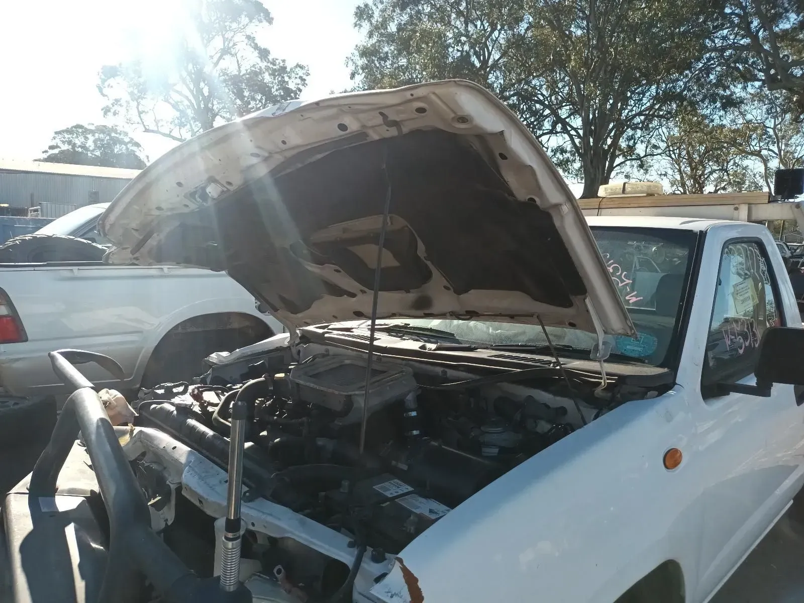 White Truck With Open Hood in a Sunny Junkyard, Showing Engine Components — South West 4WD Wreckers In Brisbane, QLD