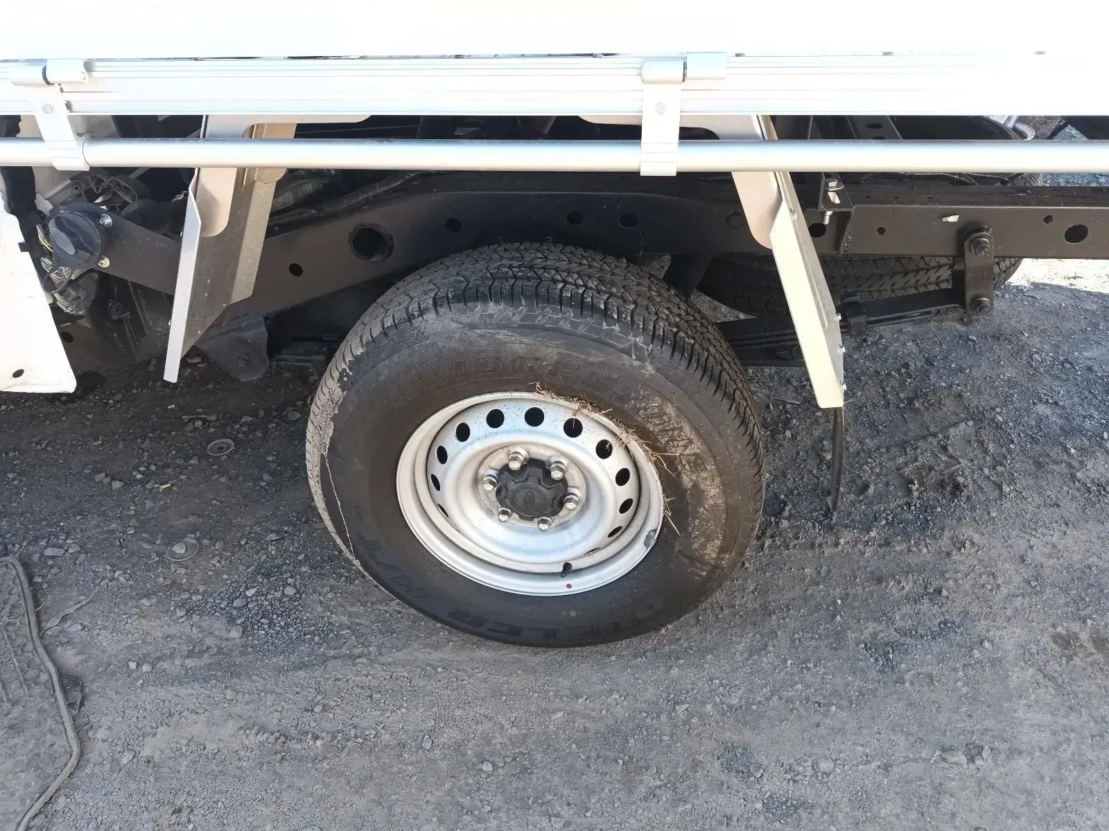 White Truck Tyre on a Gray Gravel Surface, With a Metal Rim — South West 4WD Wreckers In Brisbane, QLD