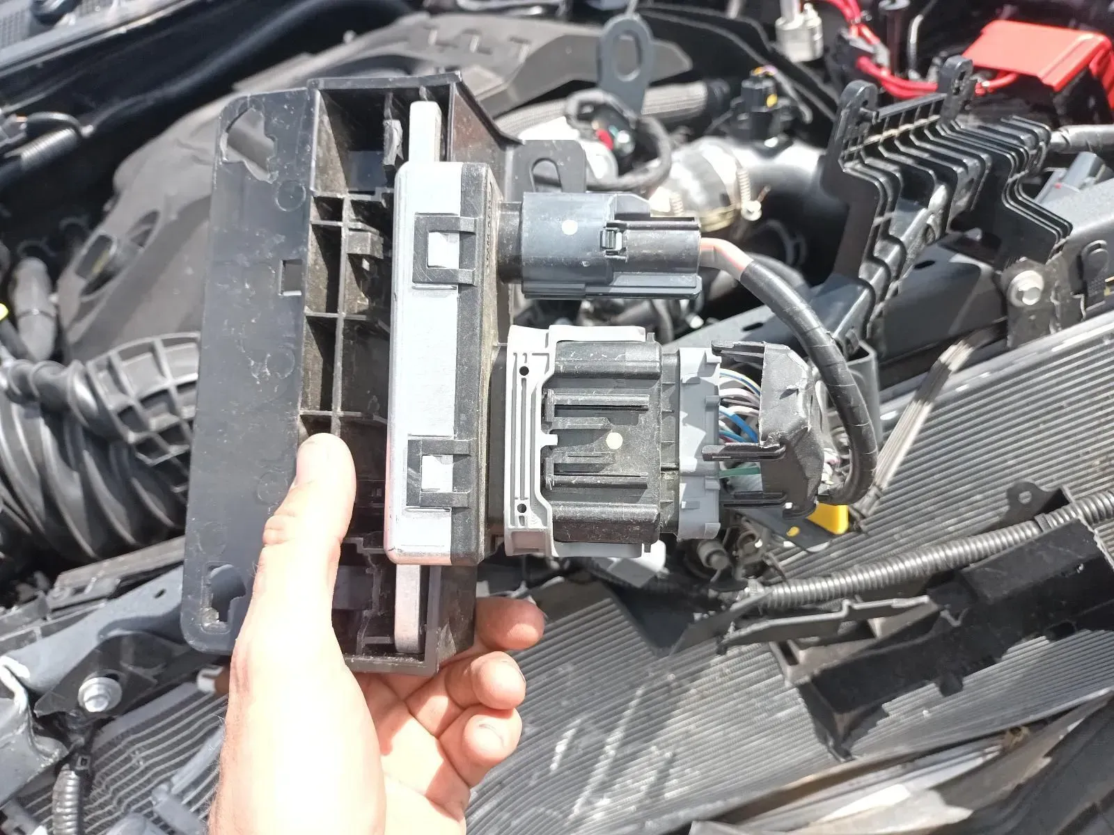 Hand Holding a Car Part With Wires, Black and Gray Components — South West 4WD Wreckers In Brisbane, QLD