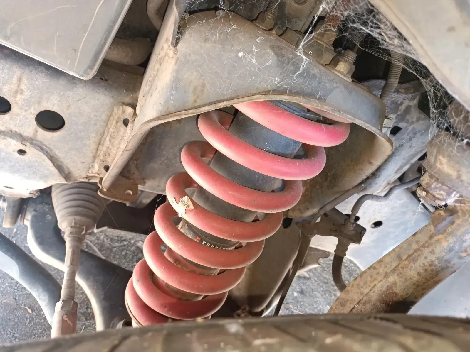 Red Coil Spring in a Car's Suspension System, Viewed From Underneath — South West 4WD Wreckers In Brisbane, QLD