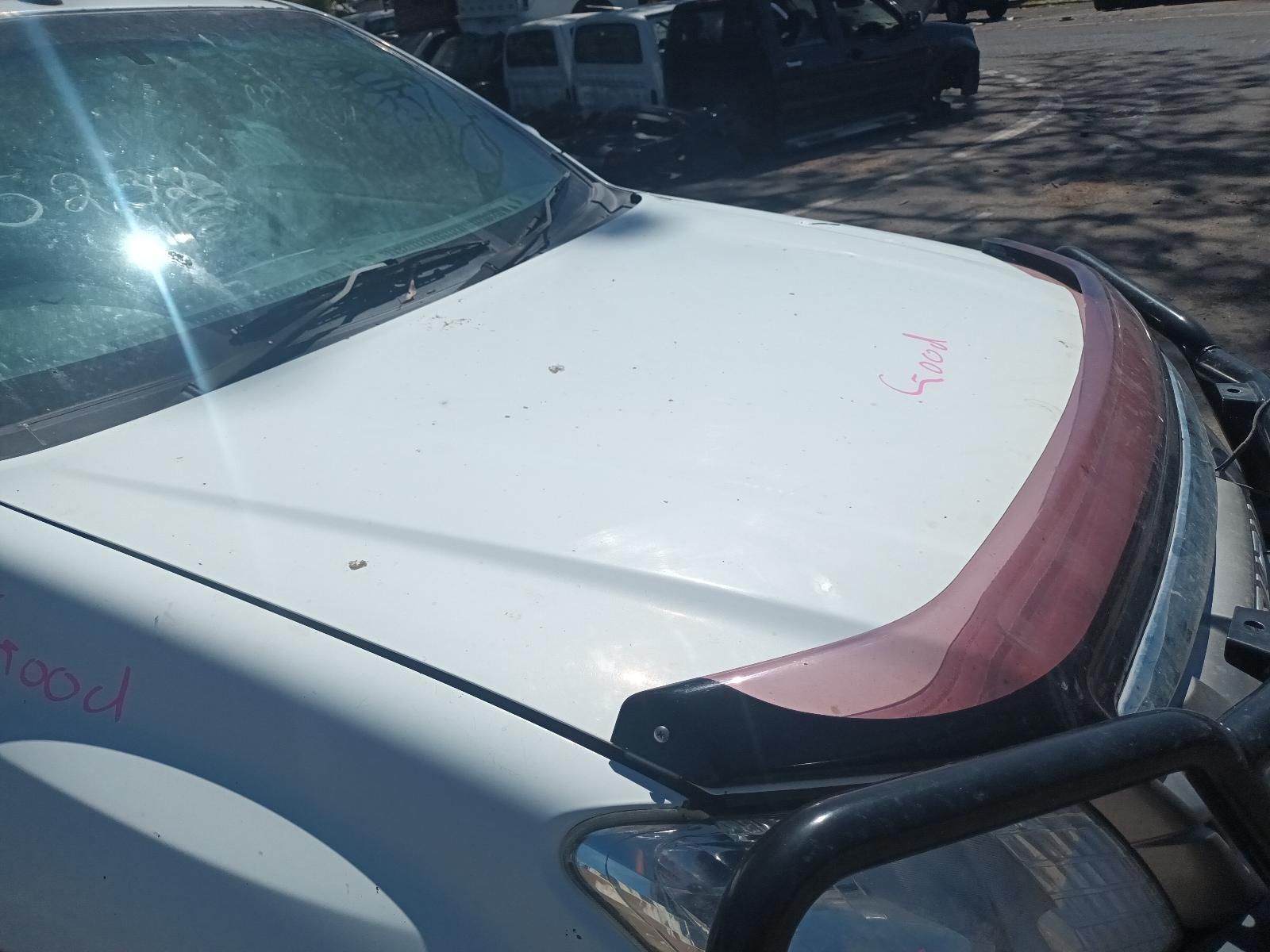 A White Car With a Red Hood Protector is Parked in a Parking Lot — South West 4WD Wreckers In Brisbane, QLD