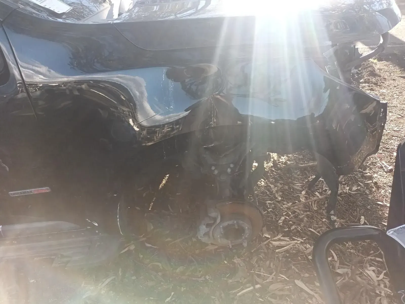 Damaged Black Car, Side View, Dented Body, Missing Wheel, Bright Sunlight — South West 4WD Wreckers In Brisbane, QLD