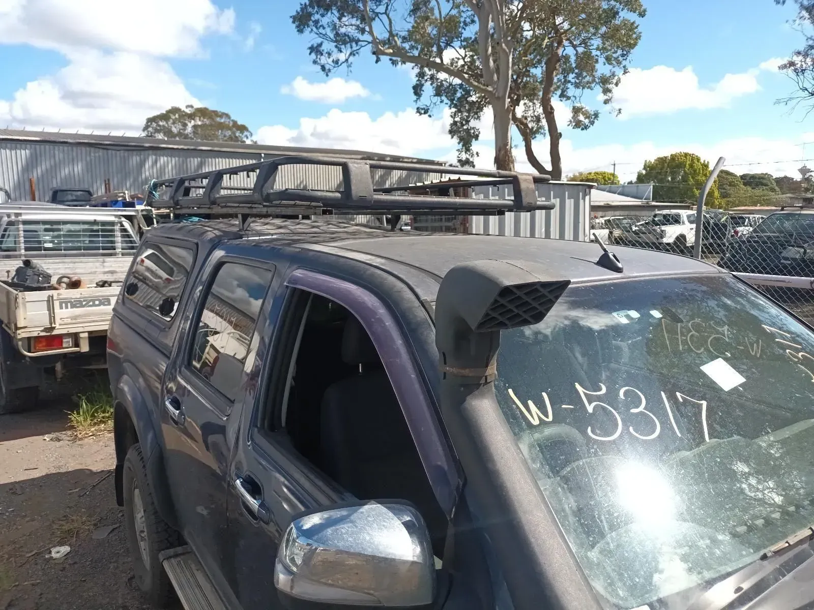 A Dark Gray Pickup Truck With a Roof Rack, Snorkel, and Windshield Tag in a Yard — South West 4WD Wreckers In Brisbane, QLD