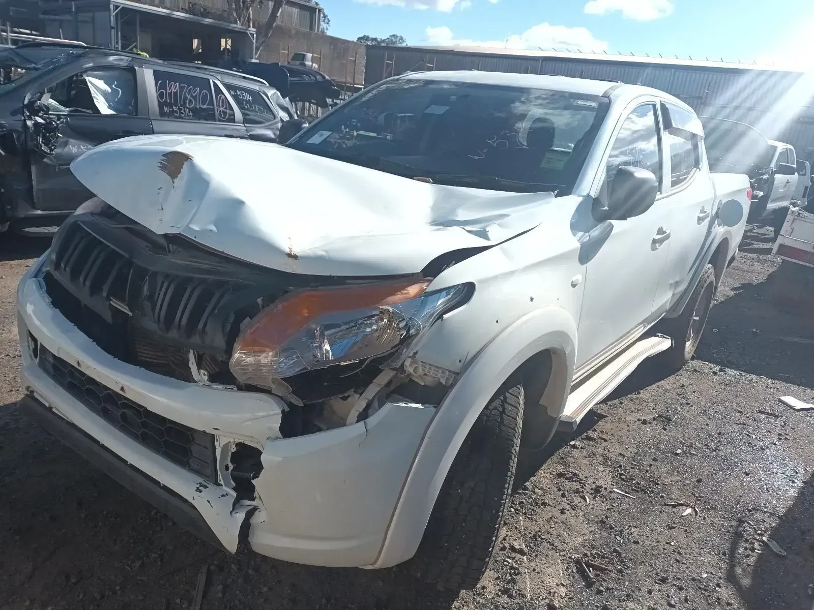 White Pickup Truck With Severe Front-end Damage in a Salvage Yard on a Sunny Day — South West 4WD Wreckers In Brisbane, QLD