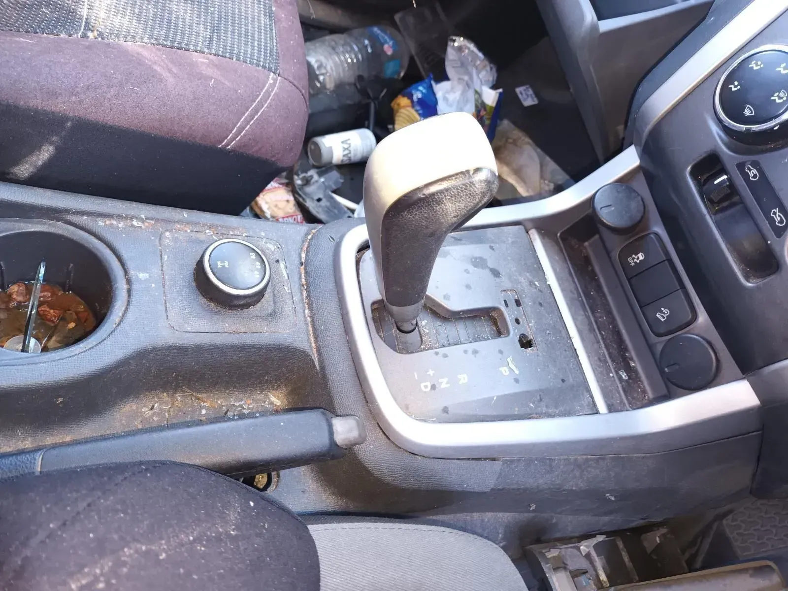 Center Console of a Dirty Car Showing the Gearshift, Cup Holder, and Control Knobs — South West 4WD Wreckers In Brisbane, QLD