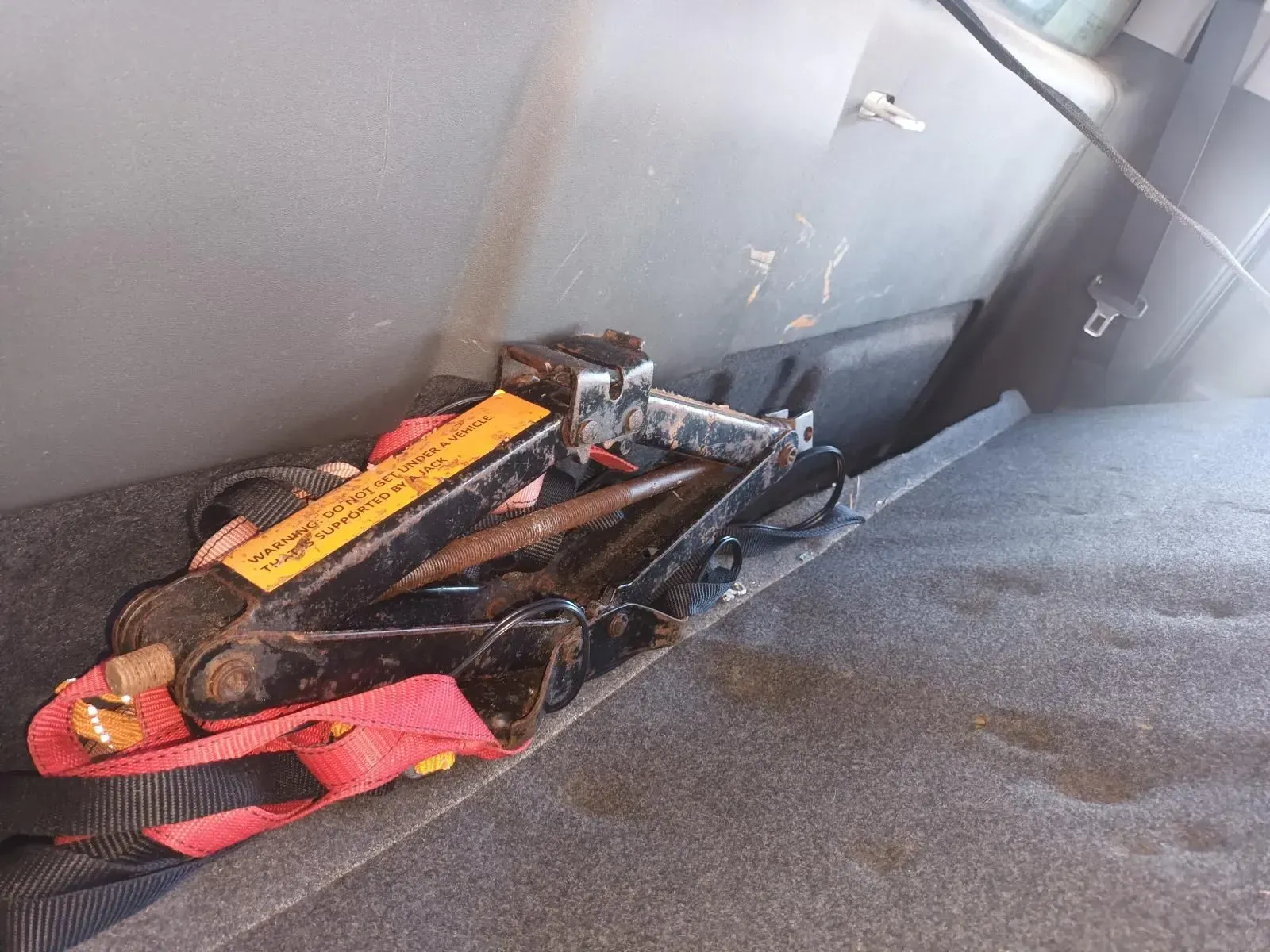 A Car Jack and a Strap in a Car's Trunk Against a Gray Interior — South West 4WD Wreckers In Brisbane, QLD