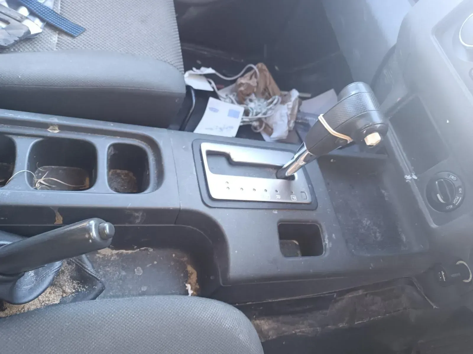 Interior View of a Dirty Car Console With Gear Shift, Cup Holders, and Debris — South West 4WD Wreckers In Brisbane, QLD