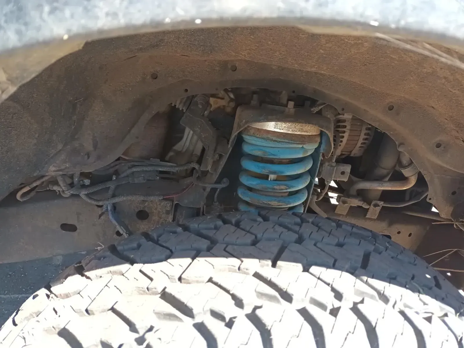 Blue Coil Spring Suspension Visible Behind a Tyre in the Wheel Well of a Truck — South West 4WD Wreckers In Brisbane, QLD