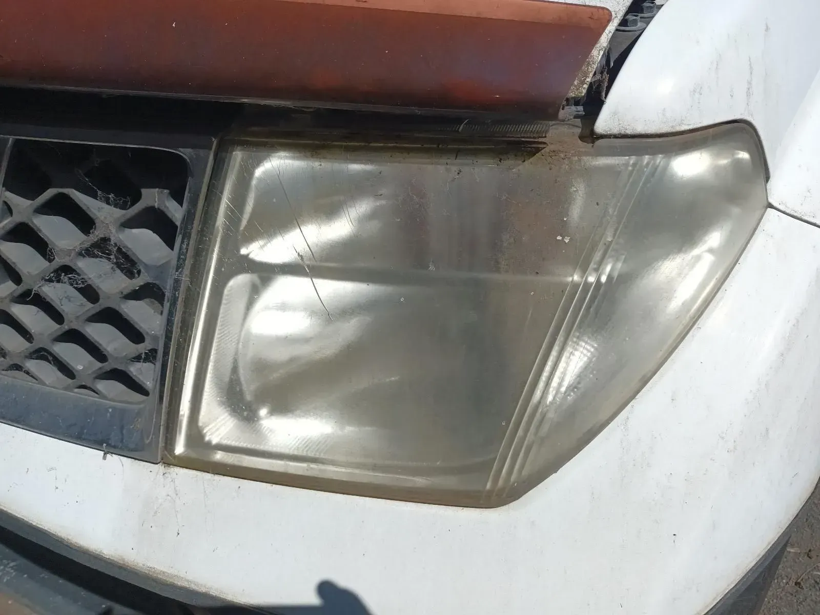 Cloudy Headlight of a White Car With a Weathered Hood — South West 4WD Wreckers In Brisbane, QLD