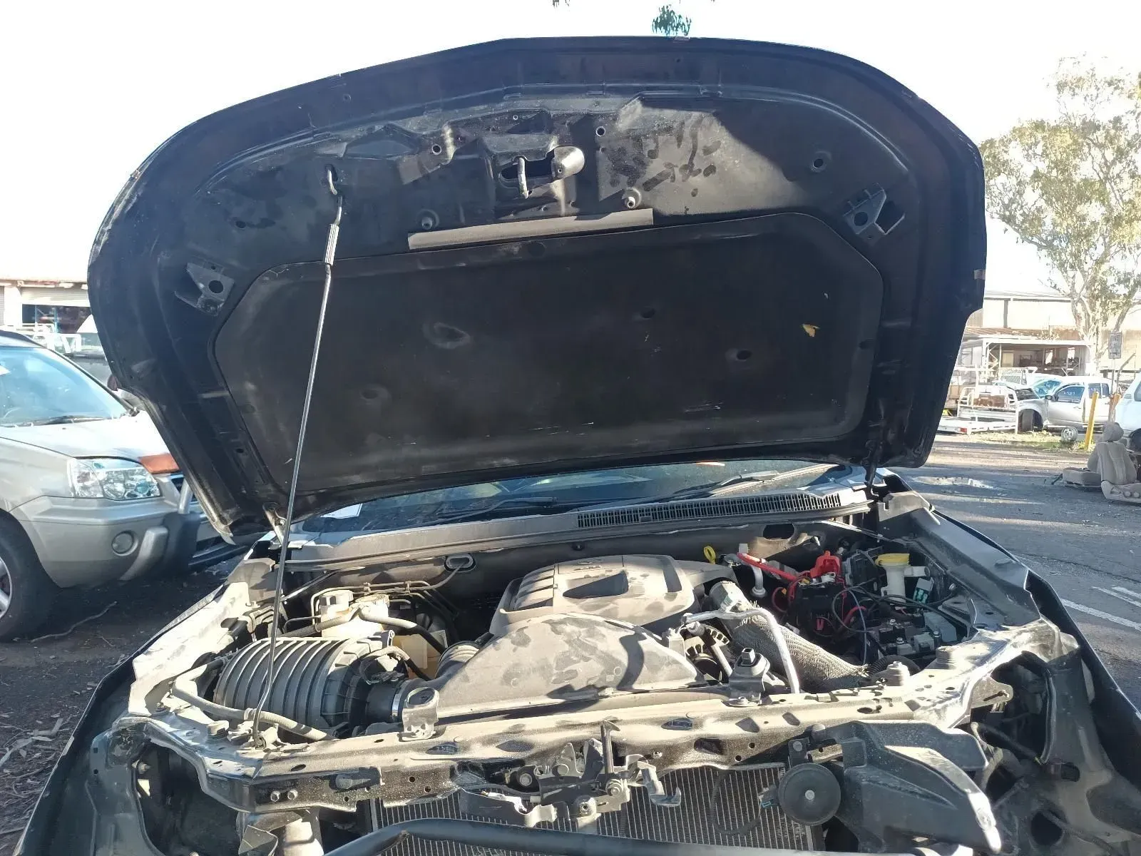 Black Car Hood Open, Showing Engine Parts in a Junkyard Setting — South West 4WD Wreckers In Brisbane, QLD