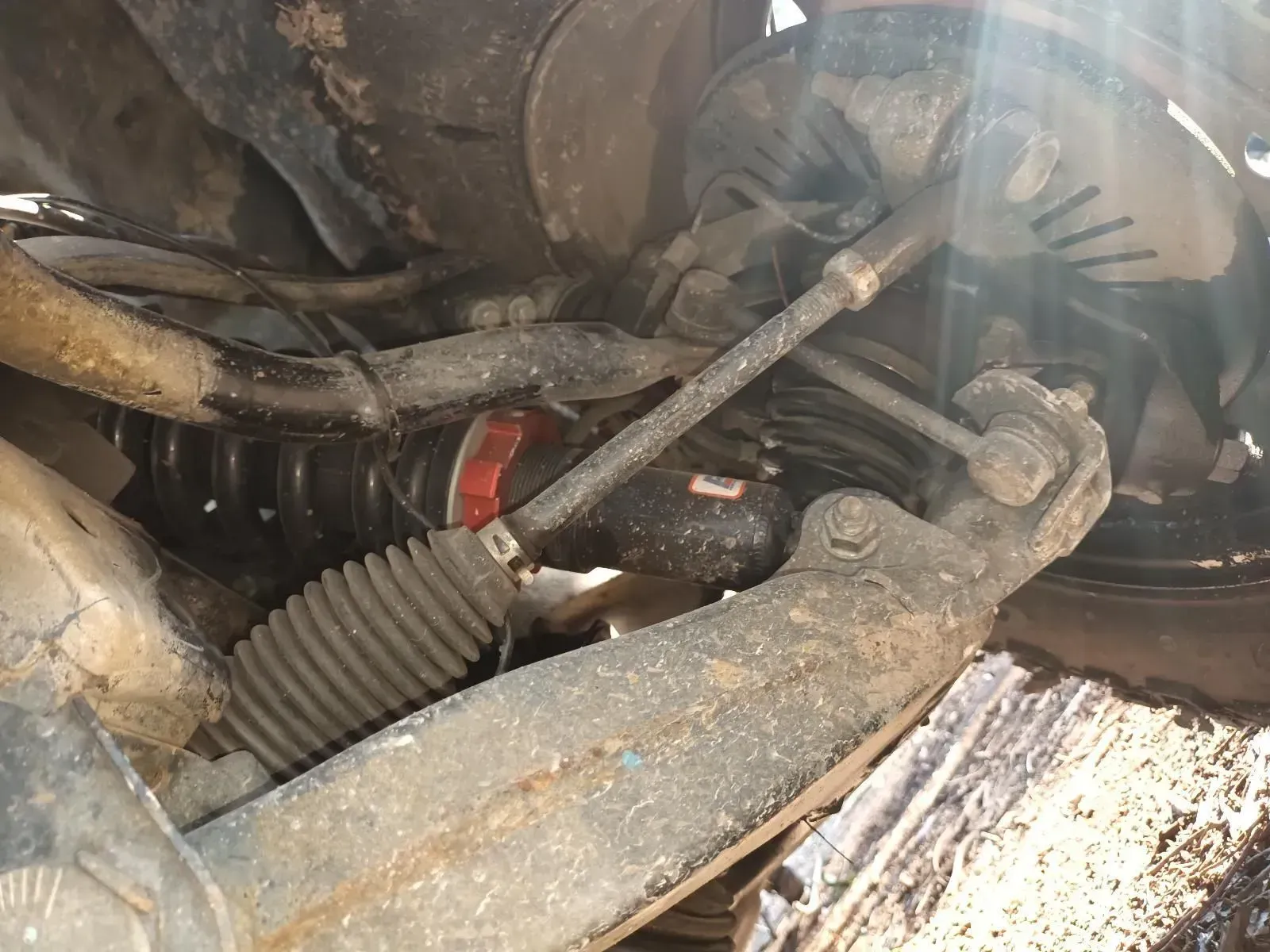 Underneath a Dirty Car, a Tie Rod, Ball Joint, and Other Suspension Components — South West 4WD Wreckers In Brisbane, QLD