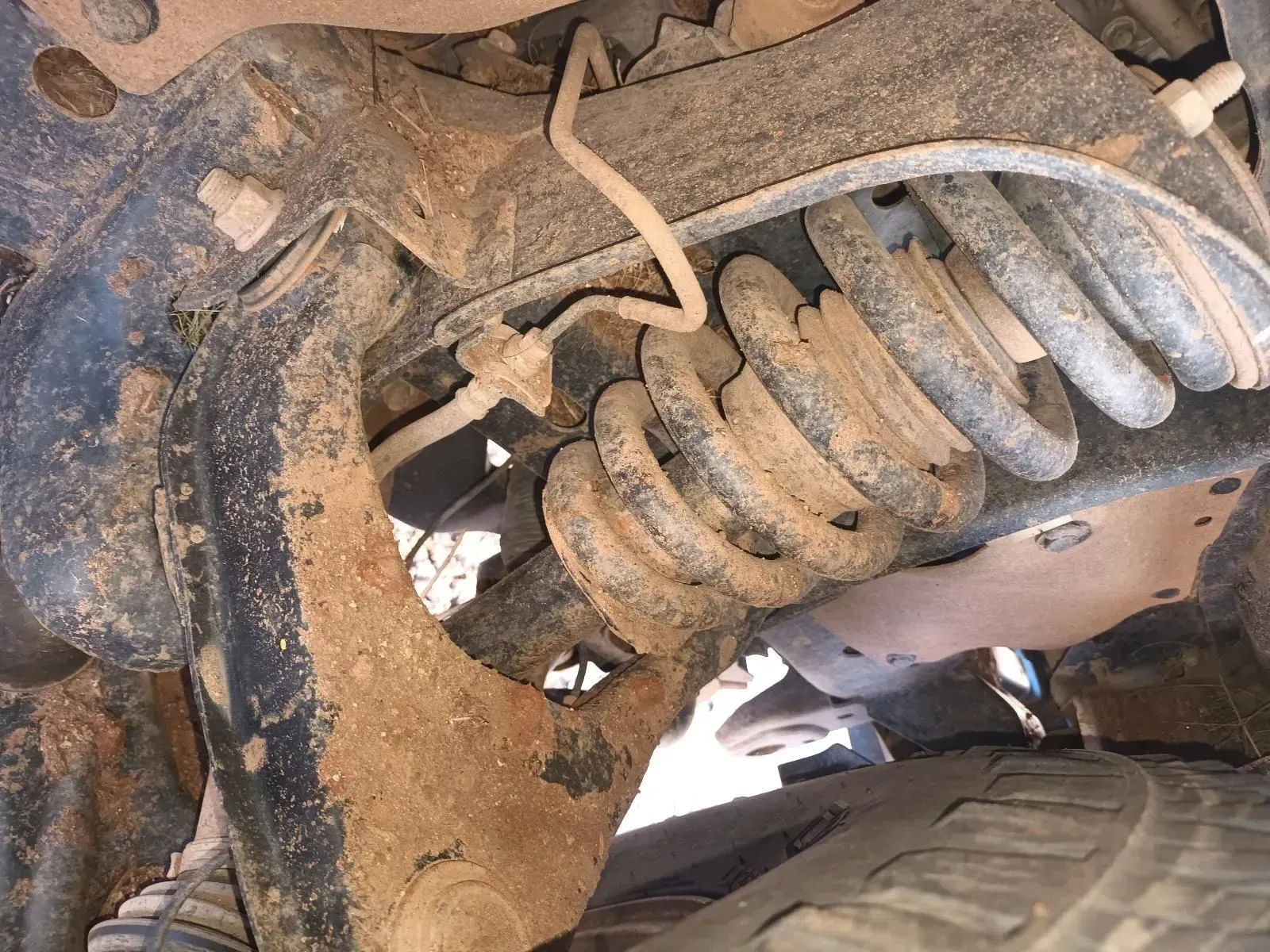 Muddy Car Suspension With Coil Spring, Control Arms, and Brake Lines — South West 4WD Wreckers In Brisbane, QLD