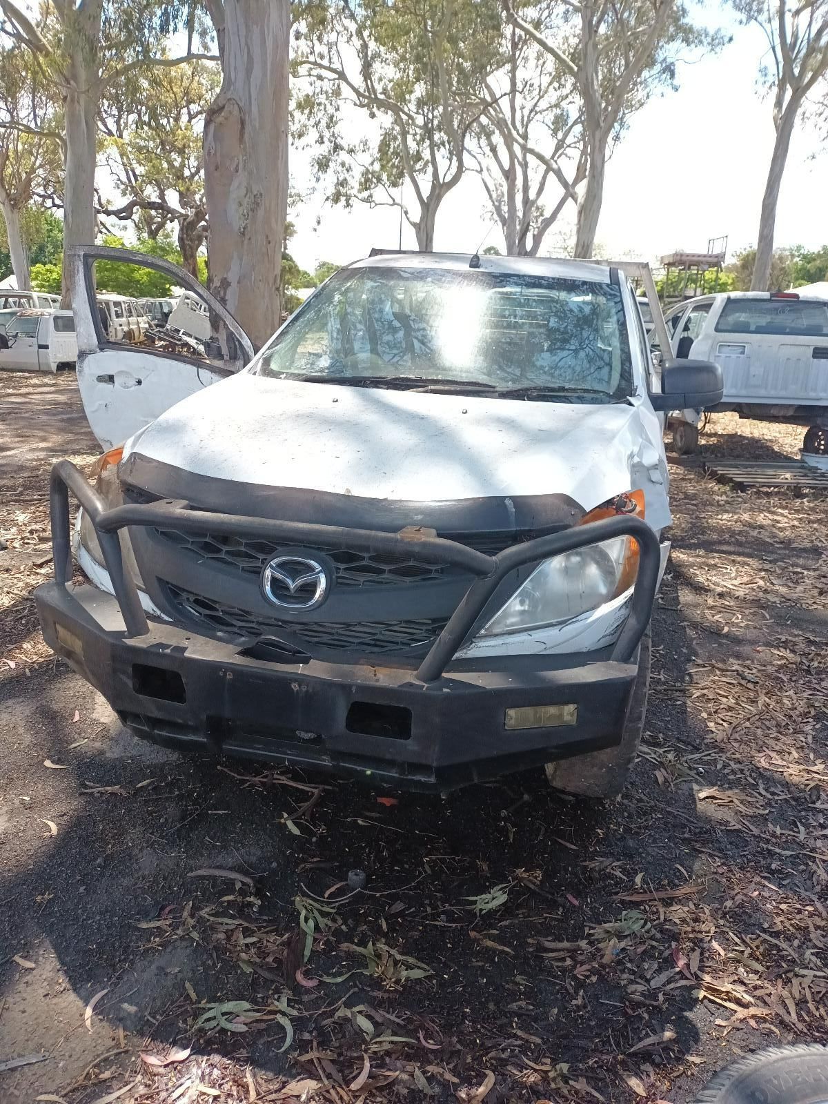A White Truck is Parked in the Dirt Next to Trees — South West 4WD Wreckers In Brisbane, QLD