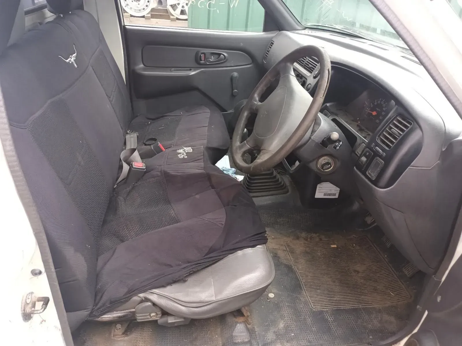Interior of a White Pickup Truck. Black Seat Covers, Dirty Floor, Steering Wheel — South West 4WD Wreckers In Brisbane, QLD