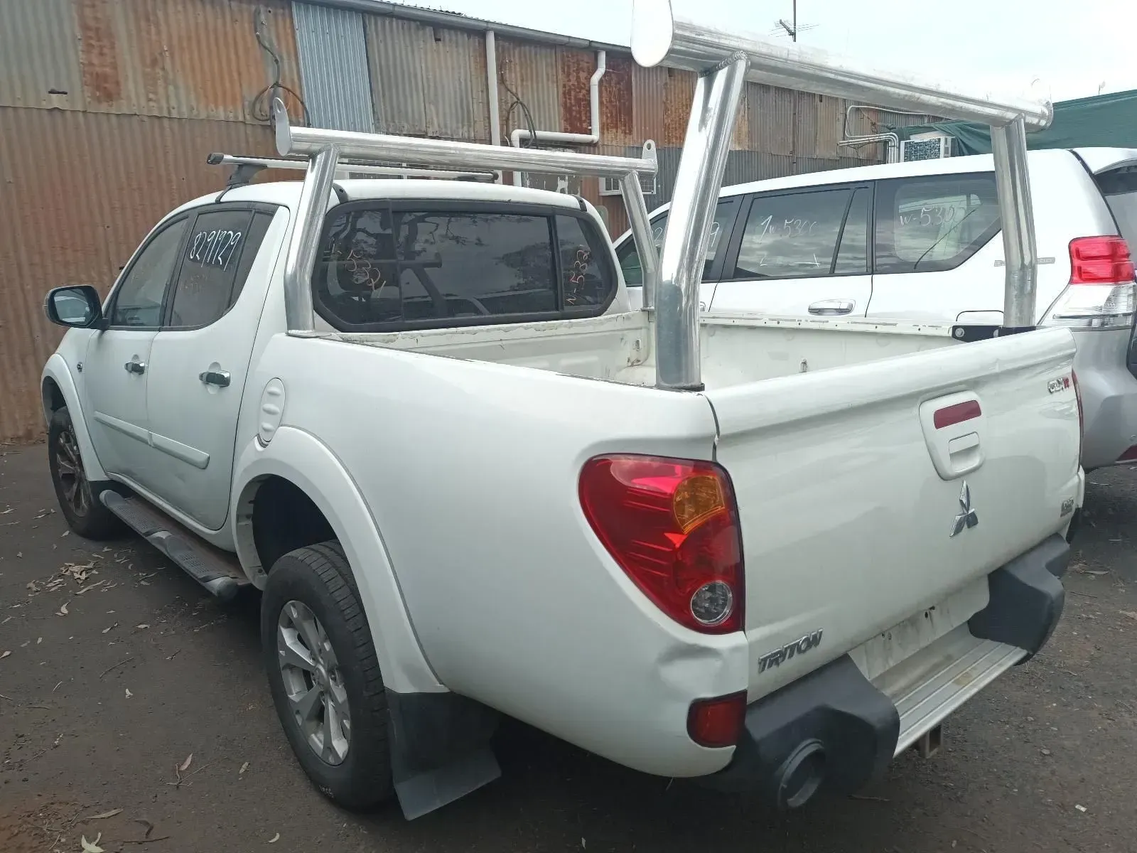White Mitsubishi Triton Pickup Truck With Ladder Rack Parked Outdoors — South West 4WD Wreckers In Brisbane, QLD