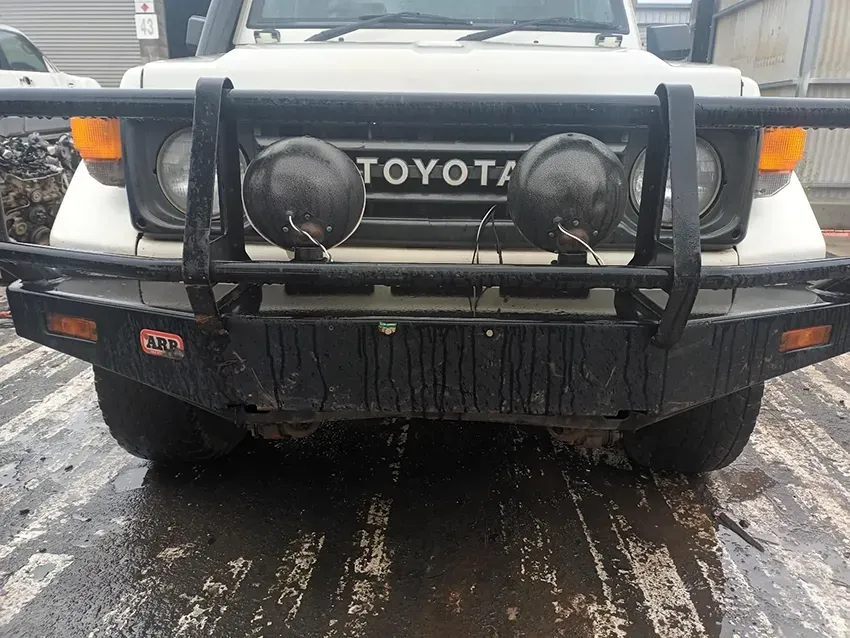 A White Toyota Truck With a Black Bumper is Parked on a Wet Road — South West 4WD Wreckers In Brisbane, QLD
