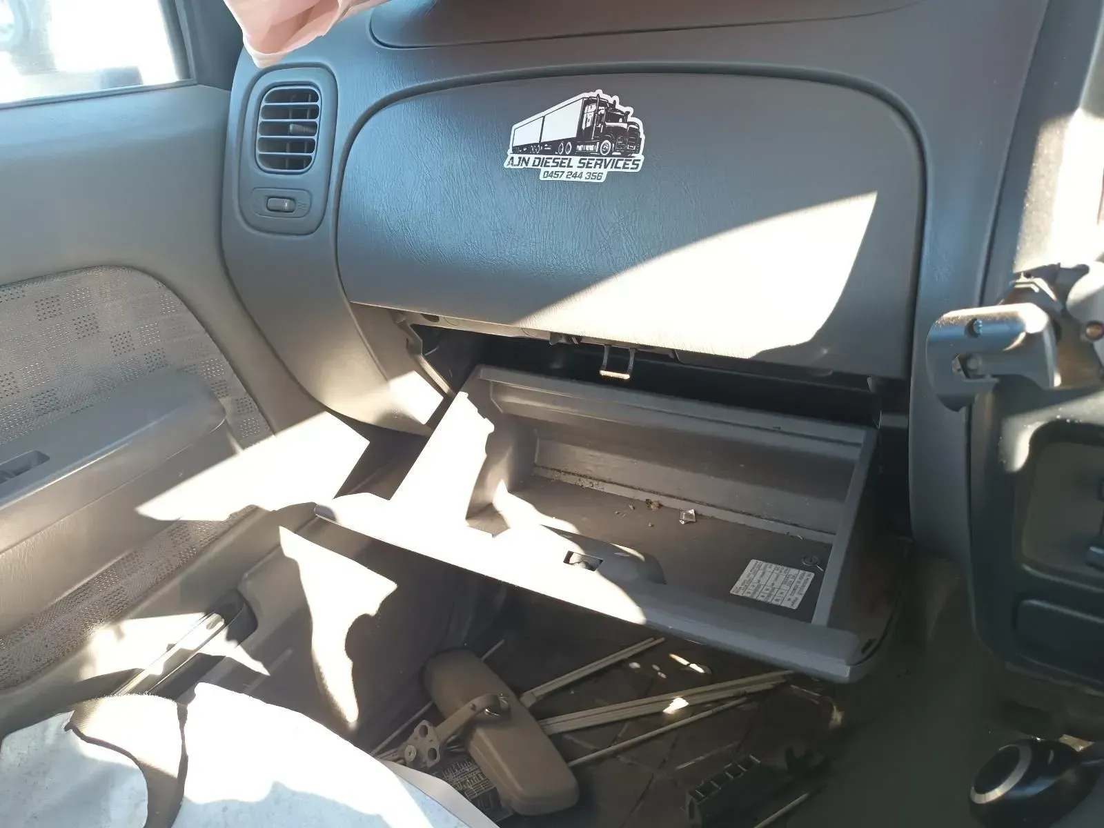 Inside of a Car Dashboard, Glove Box Open. Sticker of a Train — South West 4WD Wreckers In Brisbane, QLD