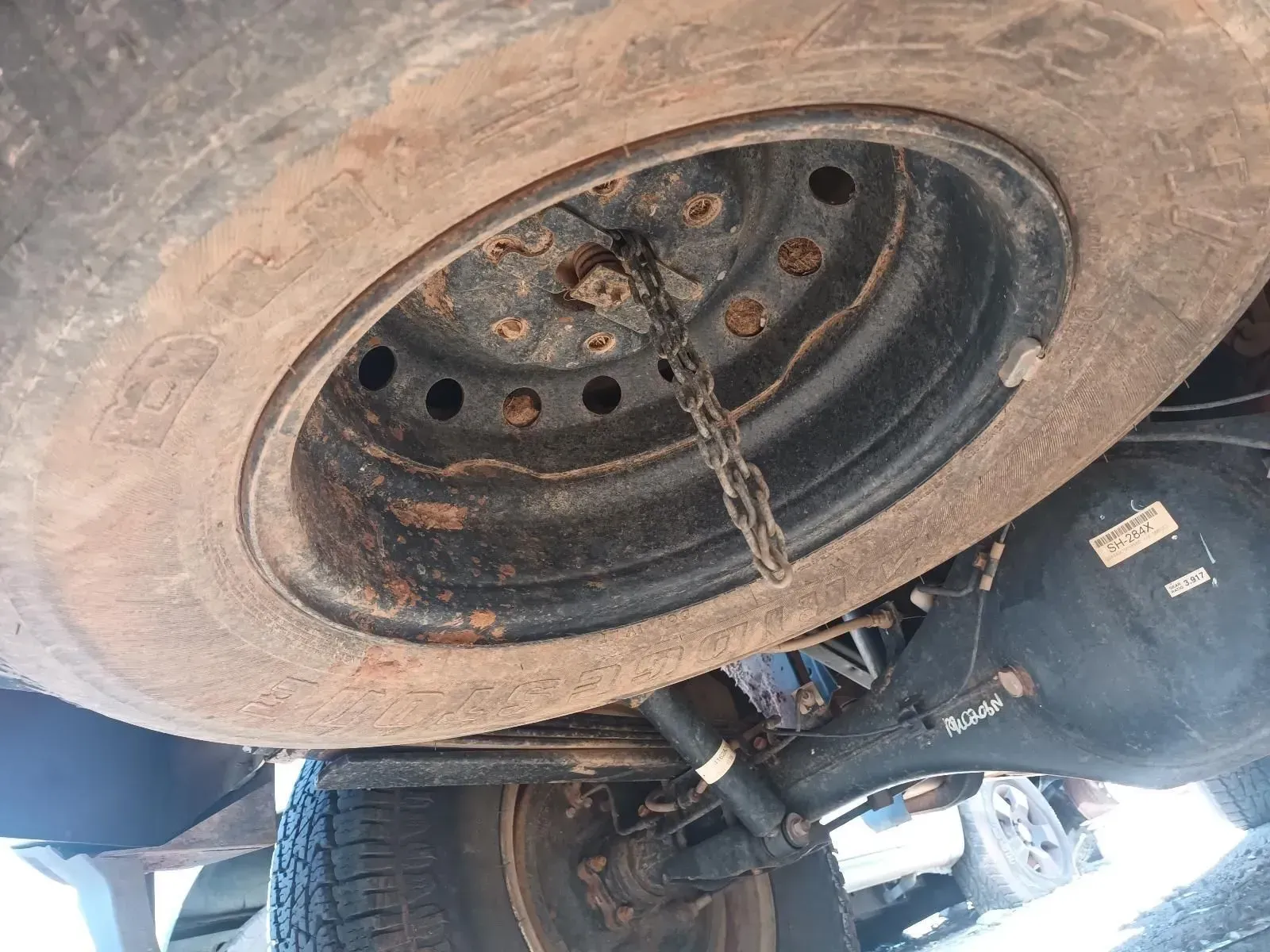 Spare Tyre Mounted Under a Vehicle, Dusty and Weathered With a Securing Chain — South West 4WD Wreckers In Brisbane, QLD
