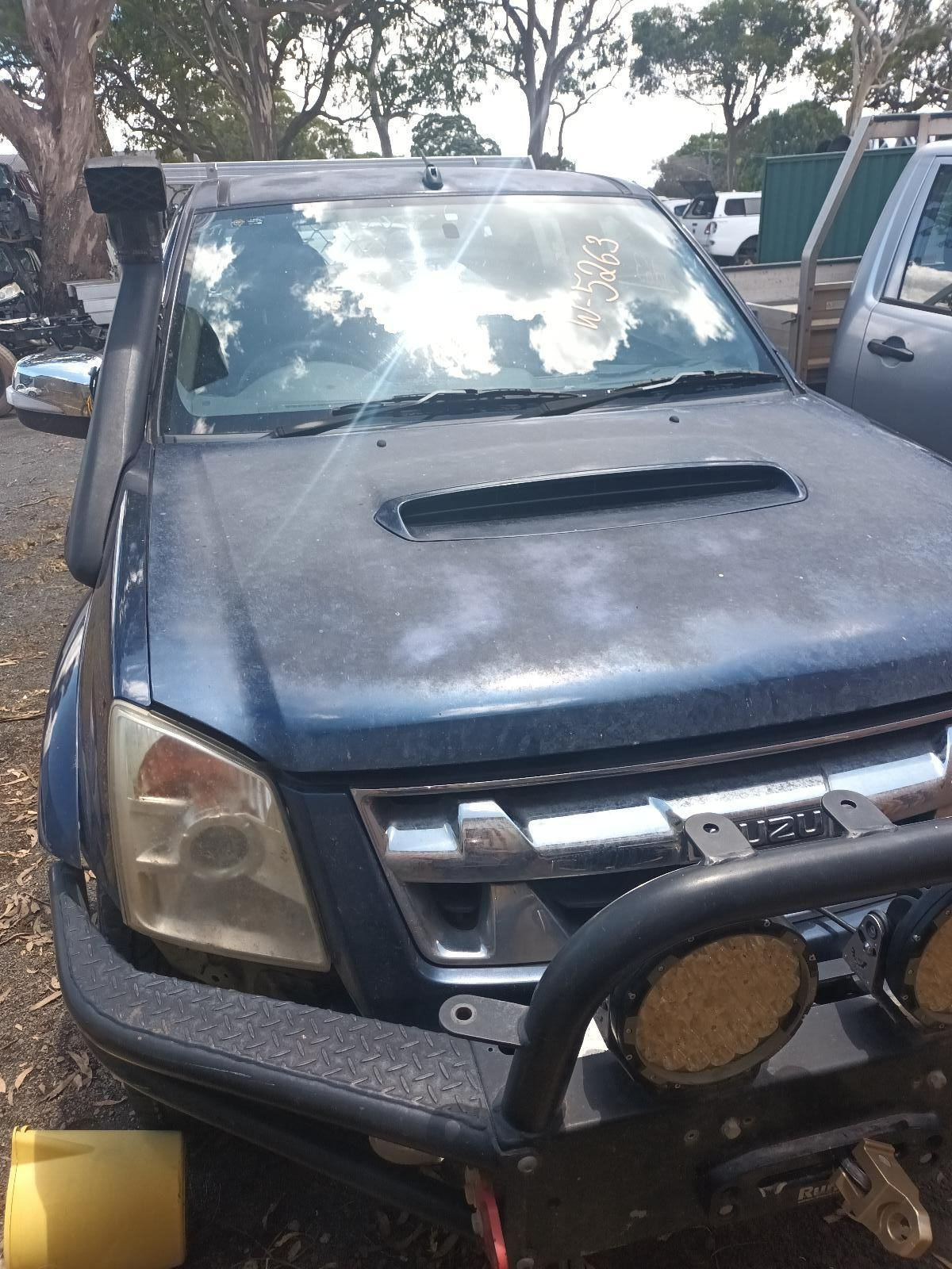 A Blue Truck is in a Parking Lot With Trees — South West 4WD Wreckers In Brisbane, QLD