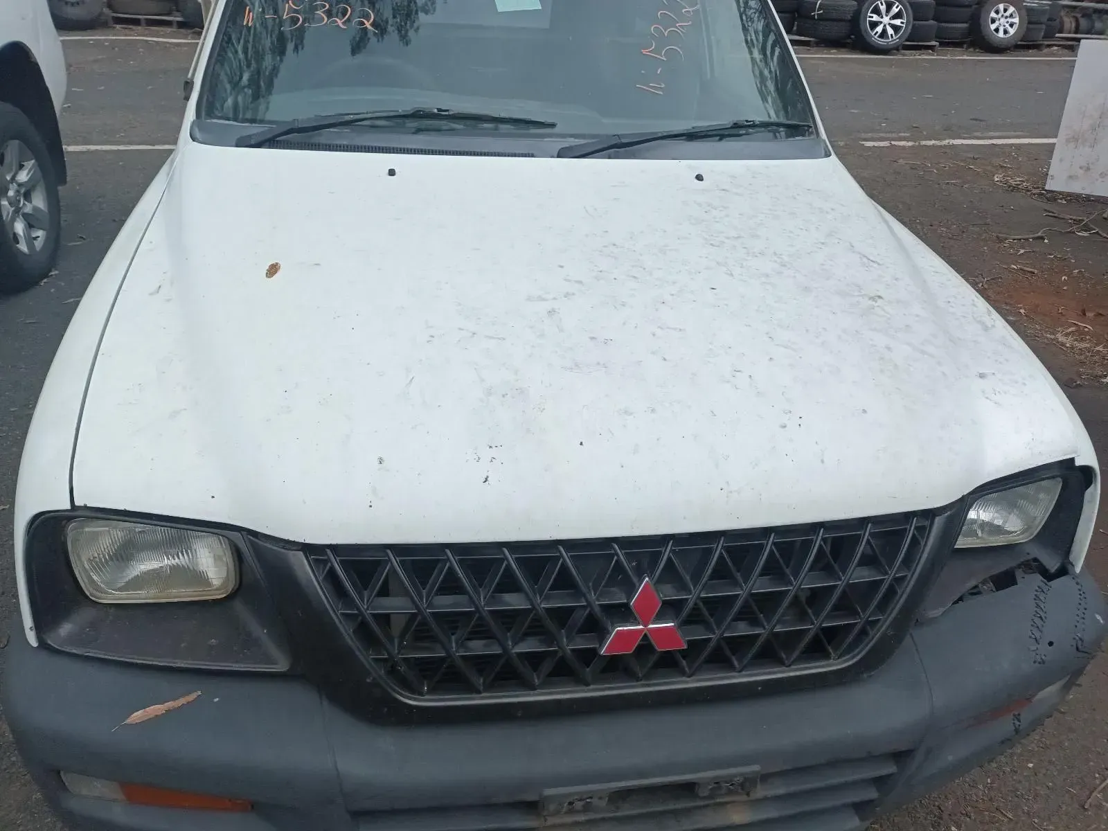 White Mitsubishi Truck With a Black Grille, Red Emblem, and Damaged Headlight — South West 4WD Wreckers In Brisbane, QLD