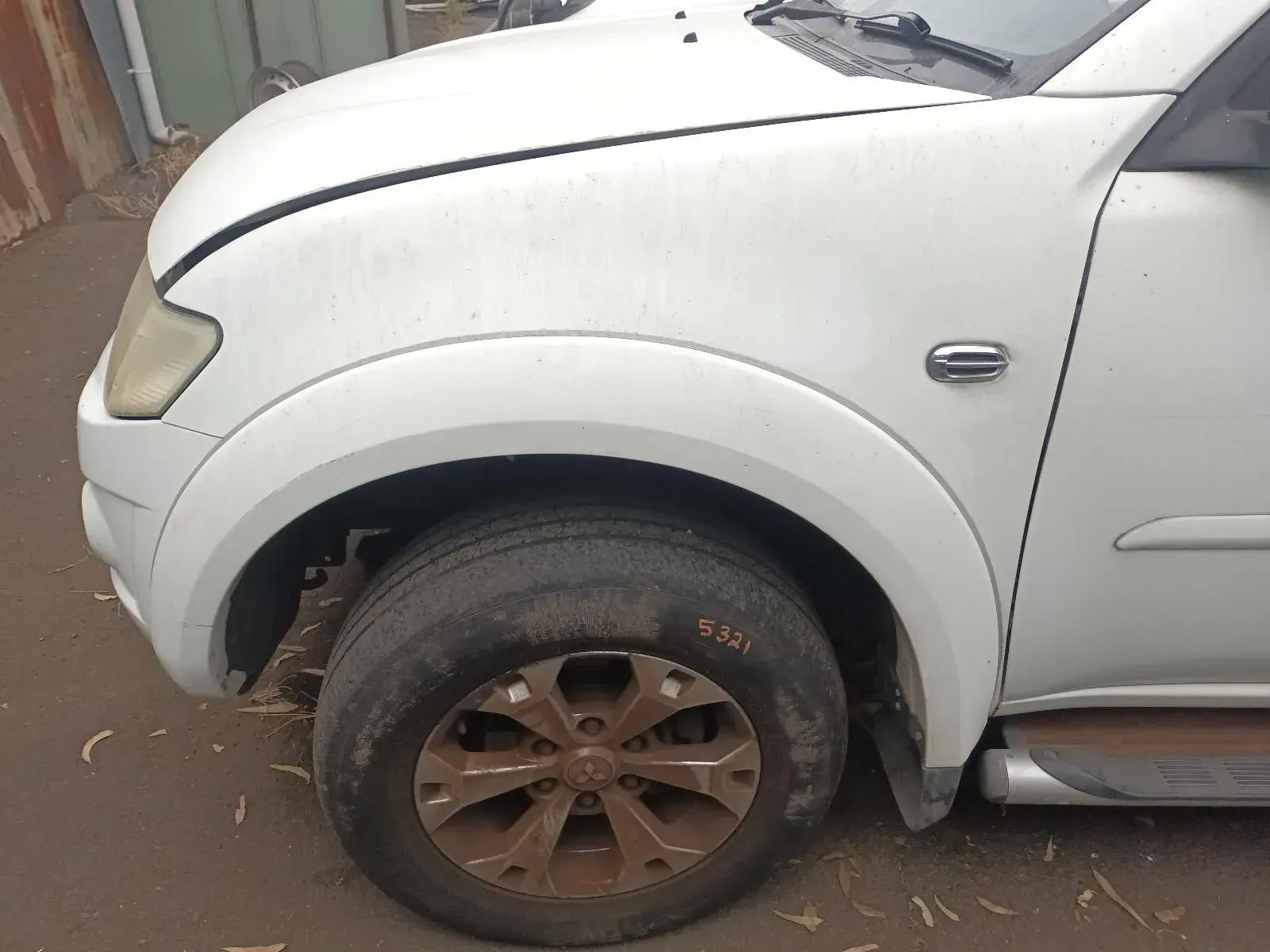 White Mitsubishi Triton Pickup Truck Front Fender, Rusted Wheel, Parked Outdoors — South West 4WD Wreckers In Brisbane, QLD