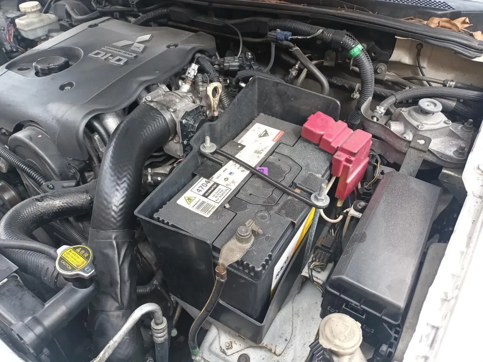 Car Engine Bay With Black Battery, Red Connectors, and Black Intake Tube — South West 4WD Wreckers In Brisbane, QLD