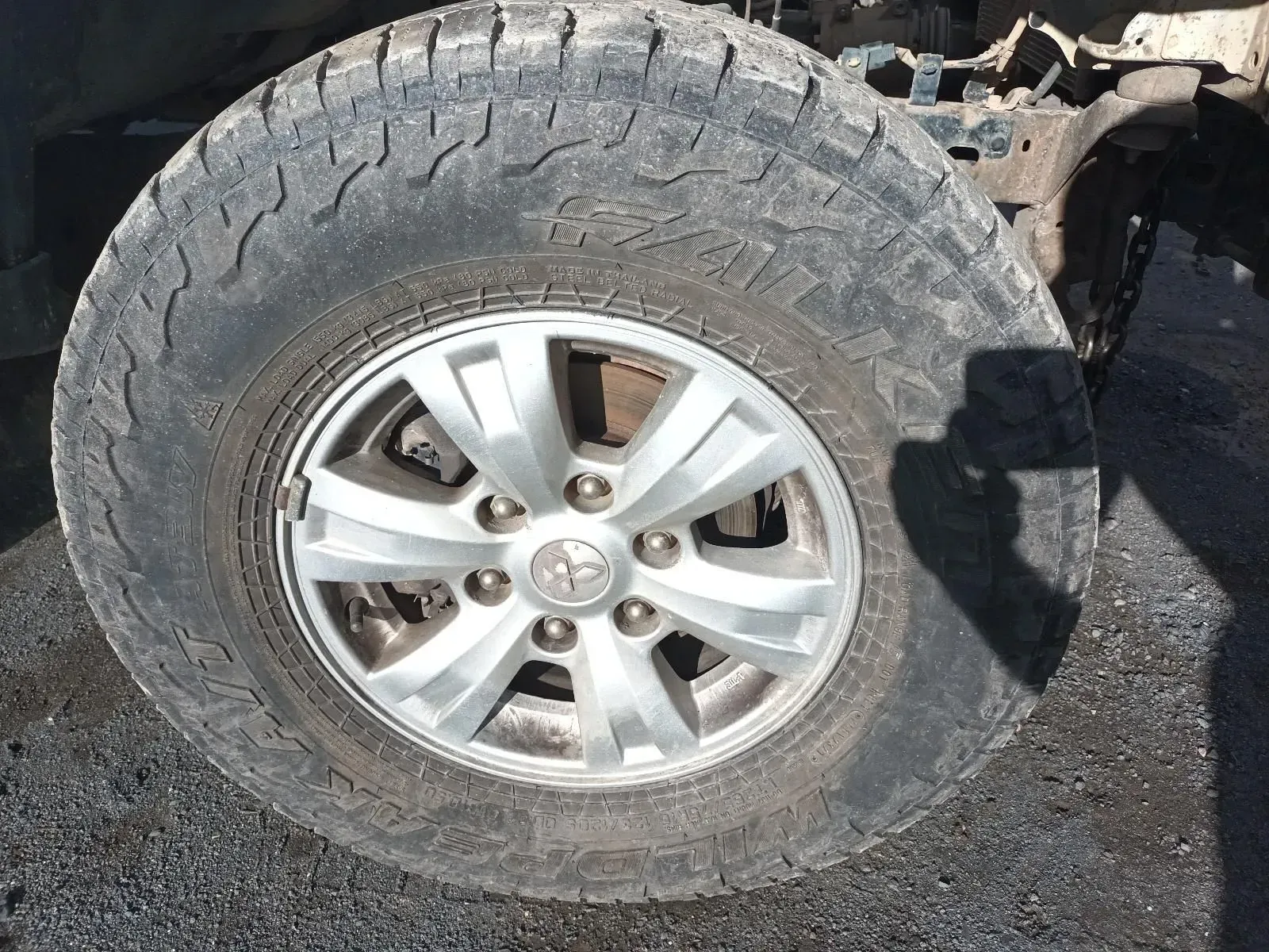 A Dirty, Gray Tyre With a Silver Rim From a Toyota Truck in a Gravel Setting — South West 4WD Wreckers In Brisbane, QLD