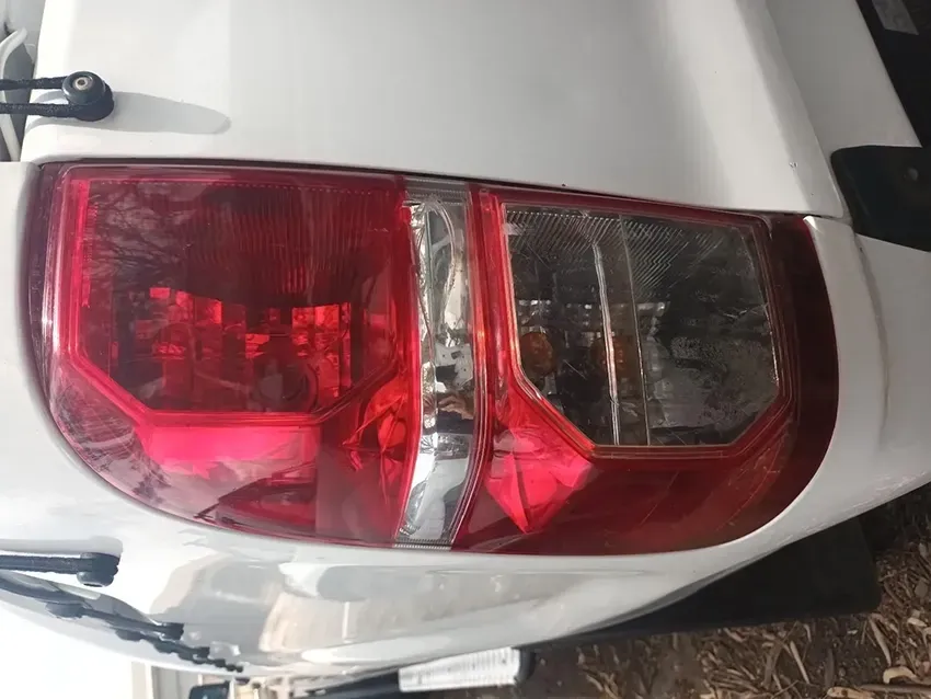 A White Car with a Red Tail Light is Parked on the Ground — South West 4WD Wreckers In Brisbane, QLD