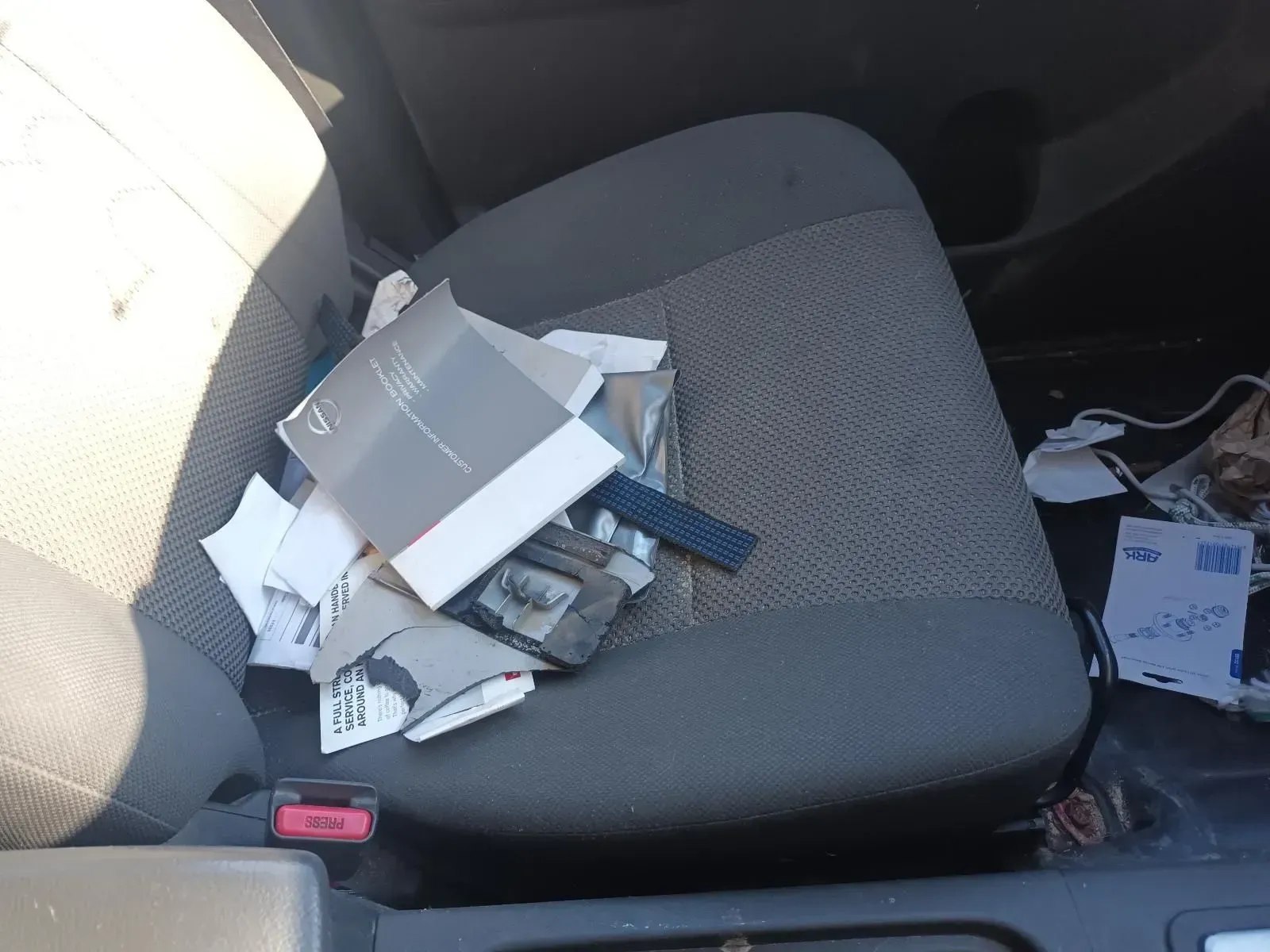 Pile of Trash on a Car Seat, Including Paper, Cardboard, and a Remote — South West 4WD Wreckers In Brisbane, QLD
