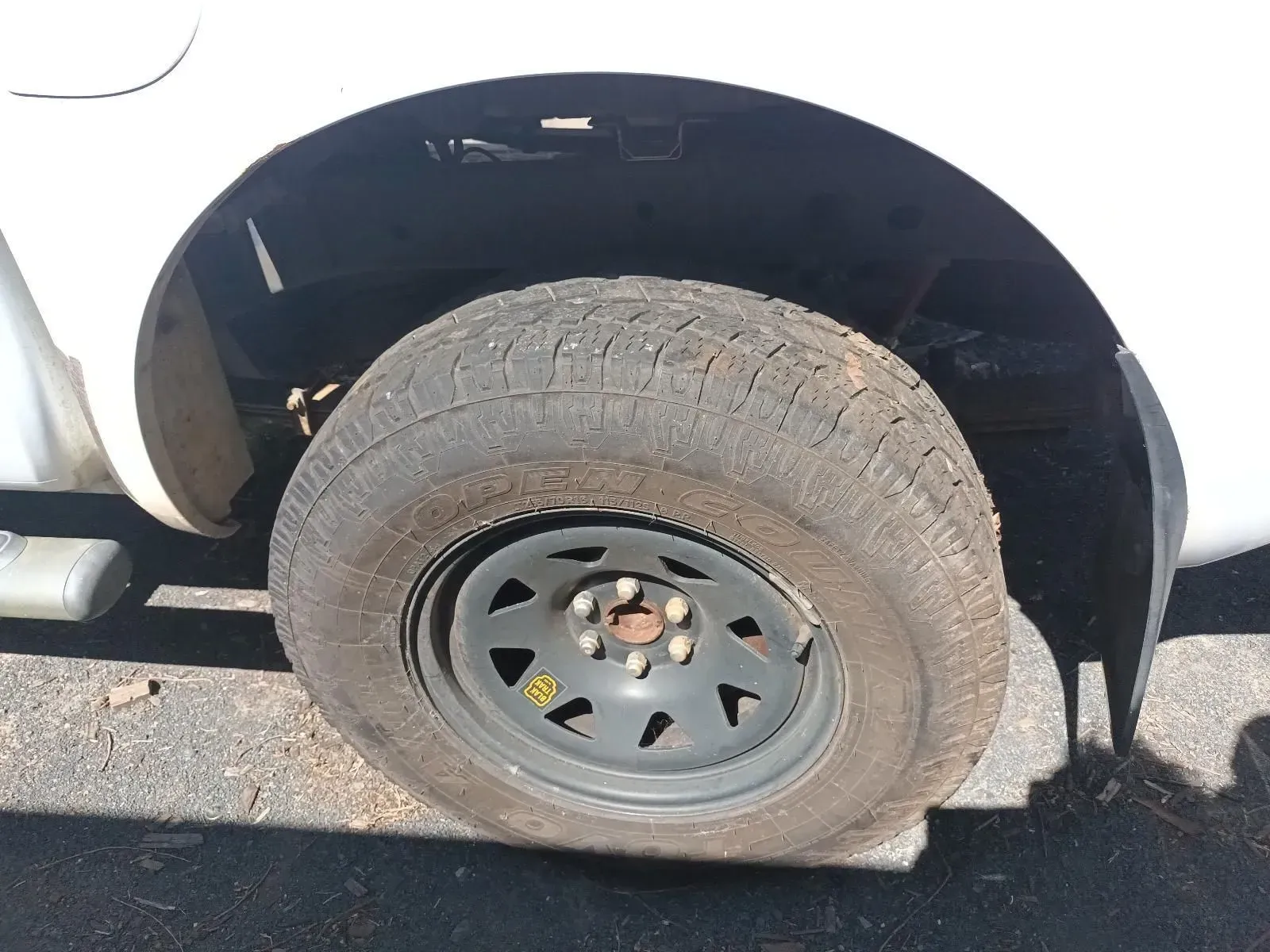 White Truck Tyre With Worn Tread and a Black Wheel, Parked Outside — South West 4WD Wreckers In Brisbane, QLD