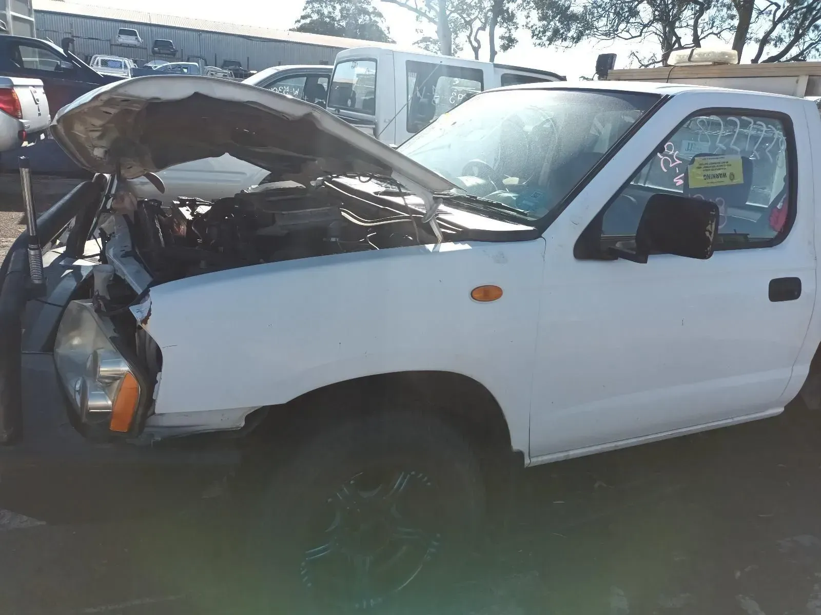 White Nissan Pickup Truck With Hood Open, in a Junkyard Setting — South West 4WD Wreckers In Brisbane, QLD