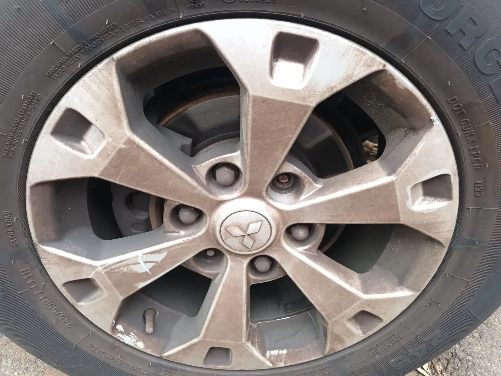 Dirty Alloy Wheel With the Mitsubishi Logo, Mounted on a Tyre — South West 4WD Wreckers In Brisbane, QLD