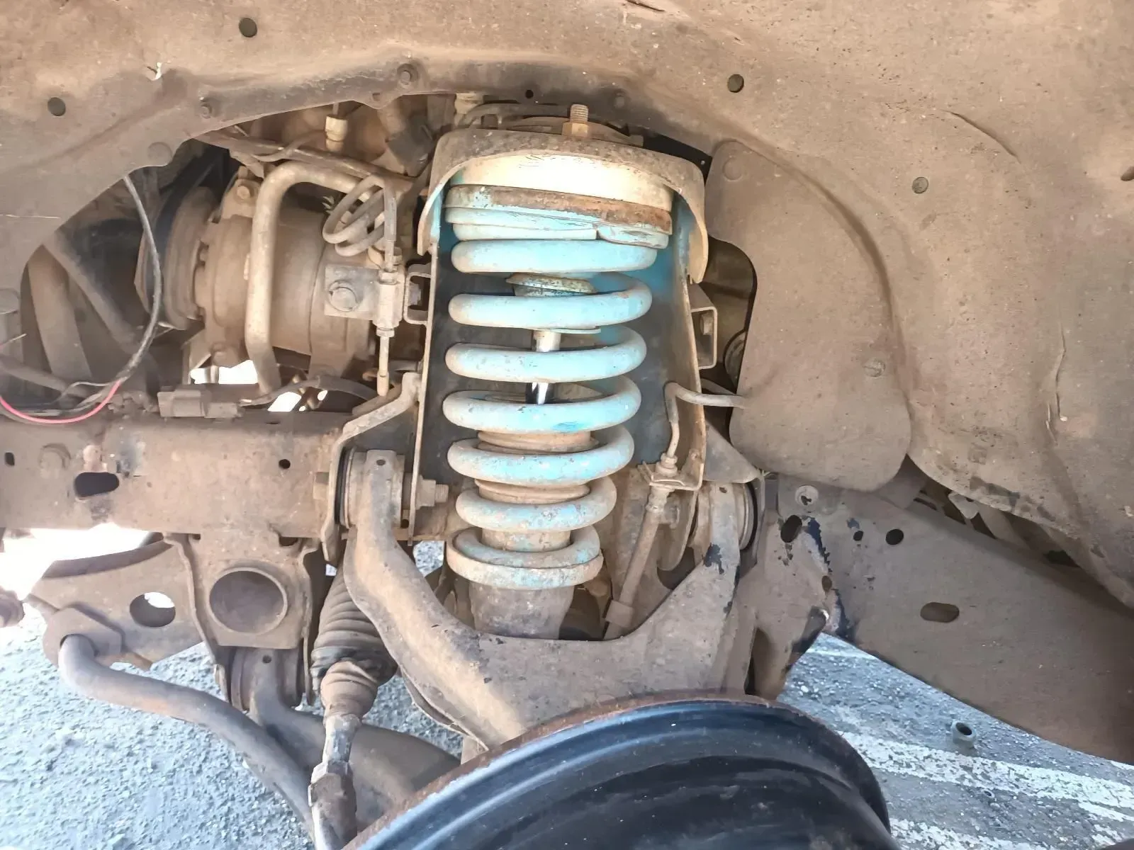 Close-up View of a Car's Suspension System With Blue Coil Spring, Dirty Components — South West 4WD Wreckers In Brisbane, QLD