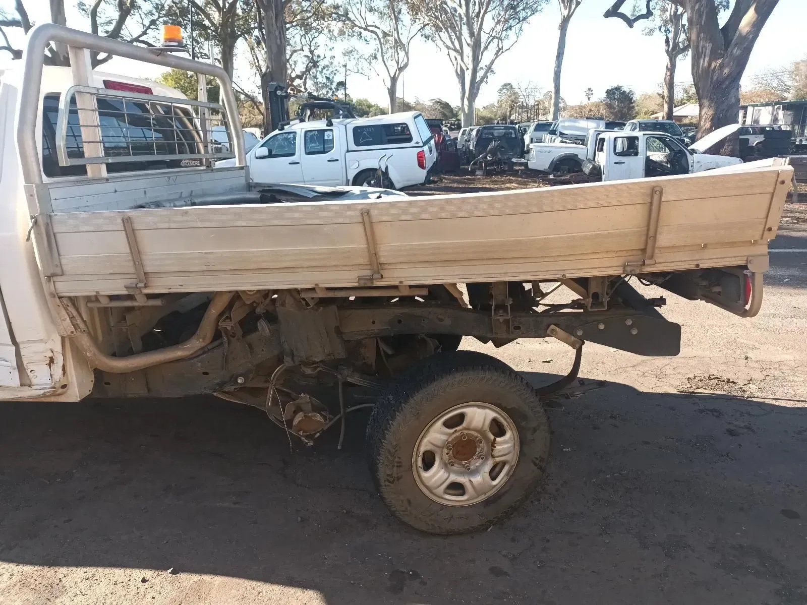 Side View of a White Flatbed Truck With a Wooden Bed, Missing a Rear Wheel — South West 4WD Wreckers In Brisbane, QLD
