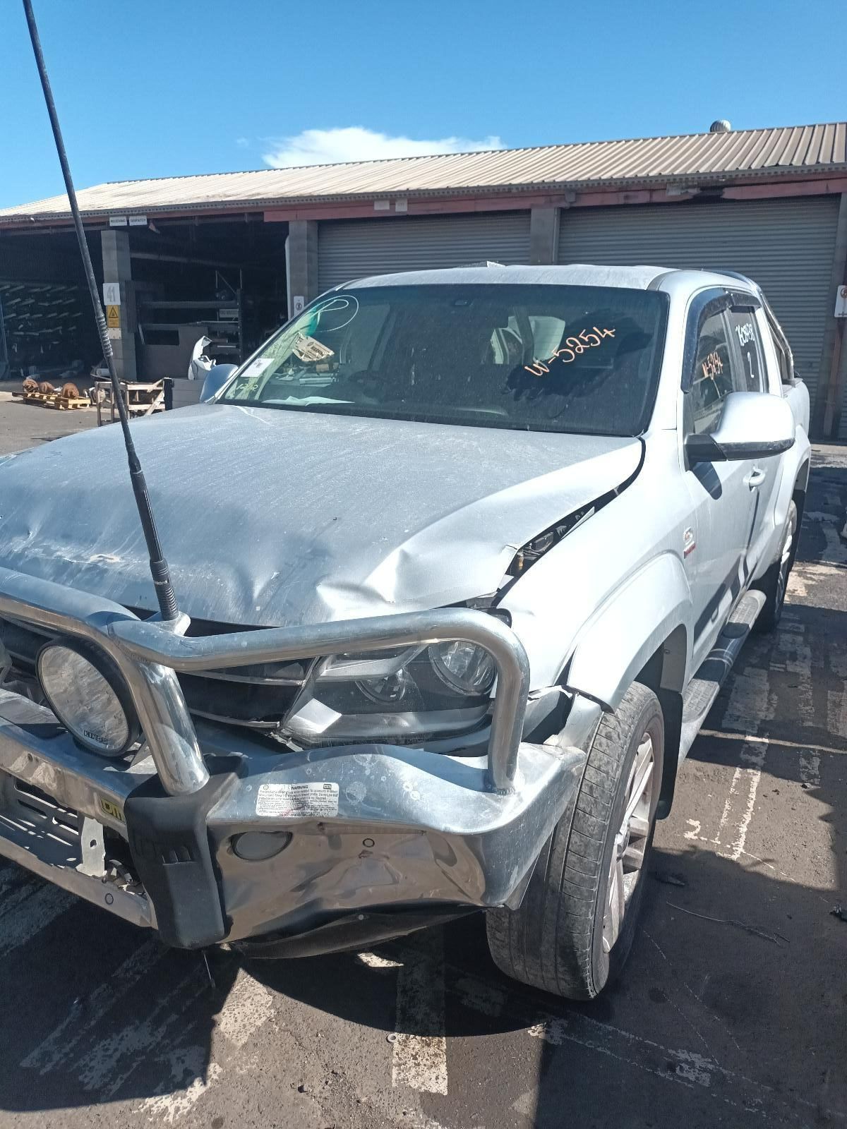 A Damaged Car is Parked in Front of a Garage — South West 4WD Wreckers In Brisbane, QLD