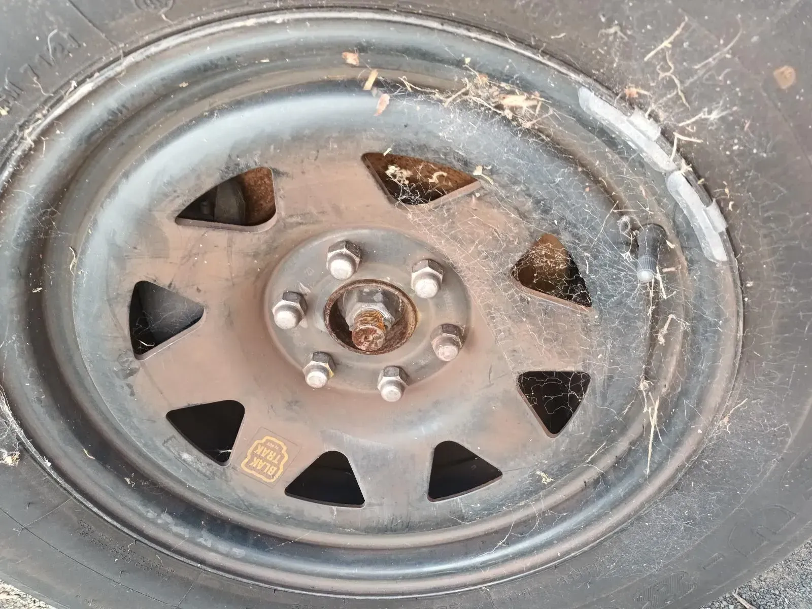 Black Steel Wheel With Tyre, Covered in Dirt and Cobwebs, Mounted on a Vehicle — South West 4WD Wreckers In Brisbane, QLD