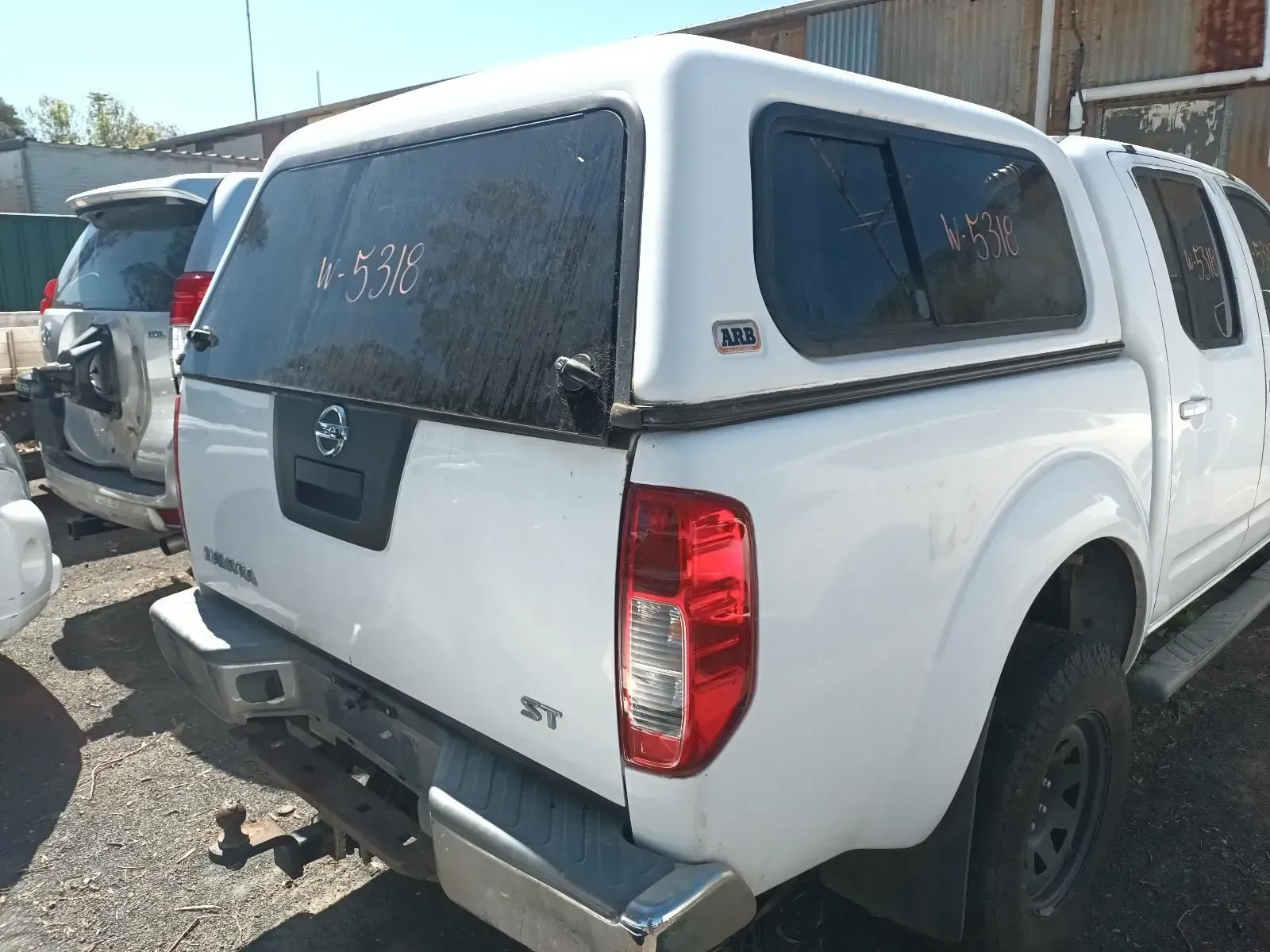 White Nissan Pickup Truck With a Canopy in a Junkyard Setting — South West 4WD Wreckers In Brisbane, QLD