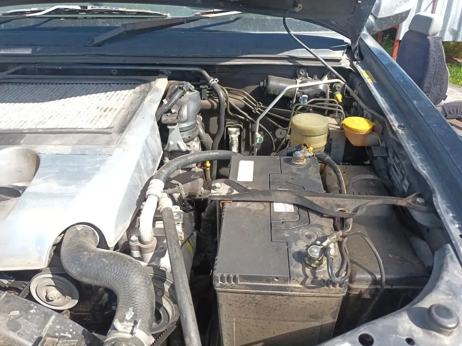 Engine Bay of a Dark Vehicle, Showing Battery, Fluids, and Mechanical Components — South West 4WD Wreckers In Brisbane, QLD