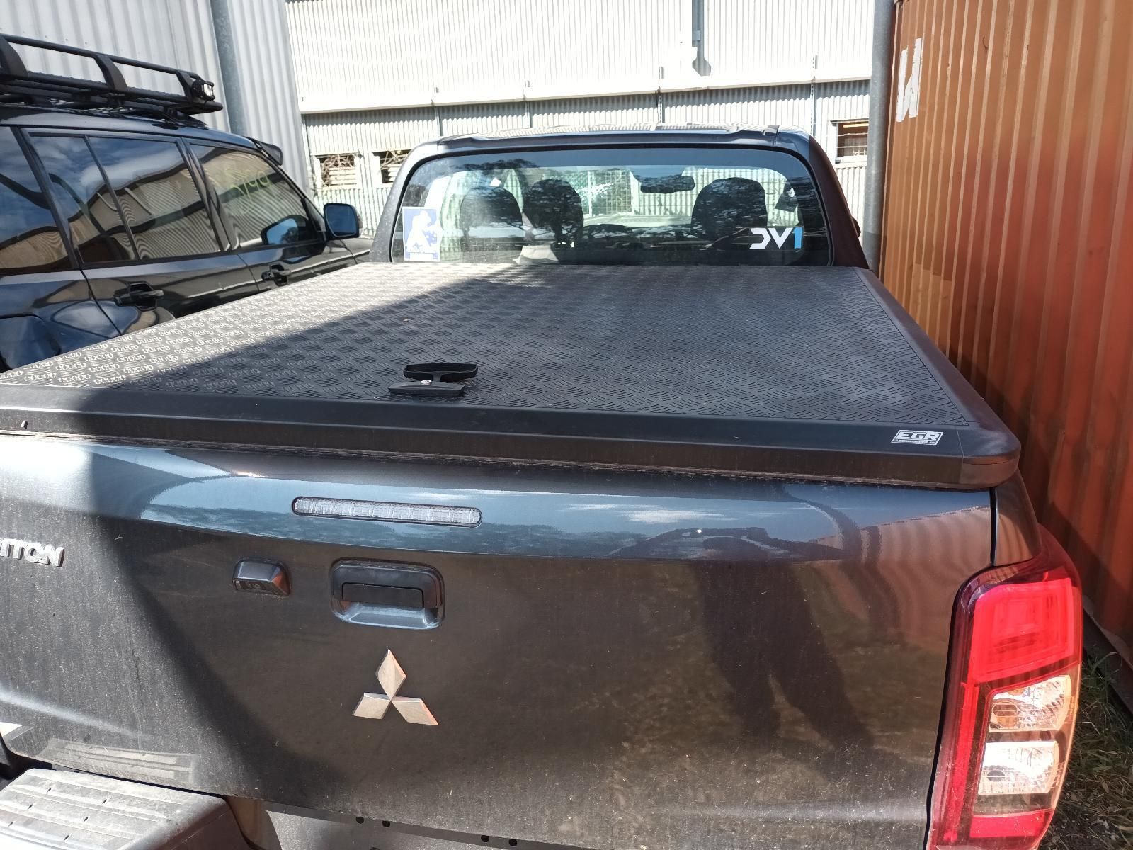 A Black Truck with a Black Bed Cover is Parked Next to a Building — South West 4WD Wreckers in Harristown, QLD