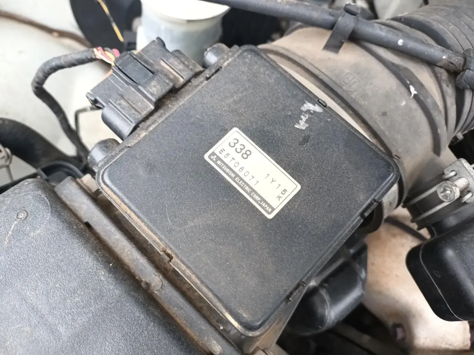 Black Air Flow Sensor in a Car Engine Bay With a Label — South West 4WD Wreckers In Brisbane, QLD