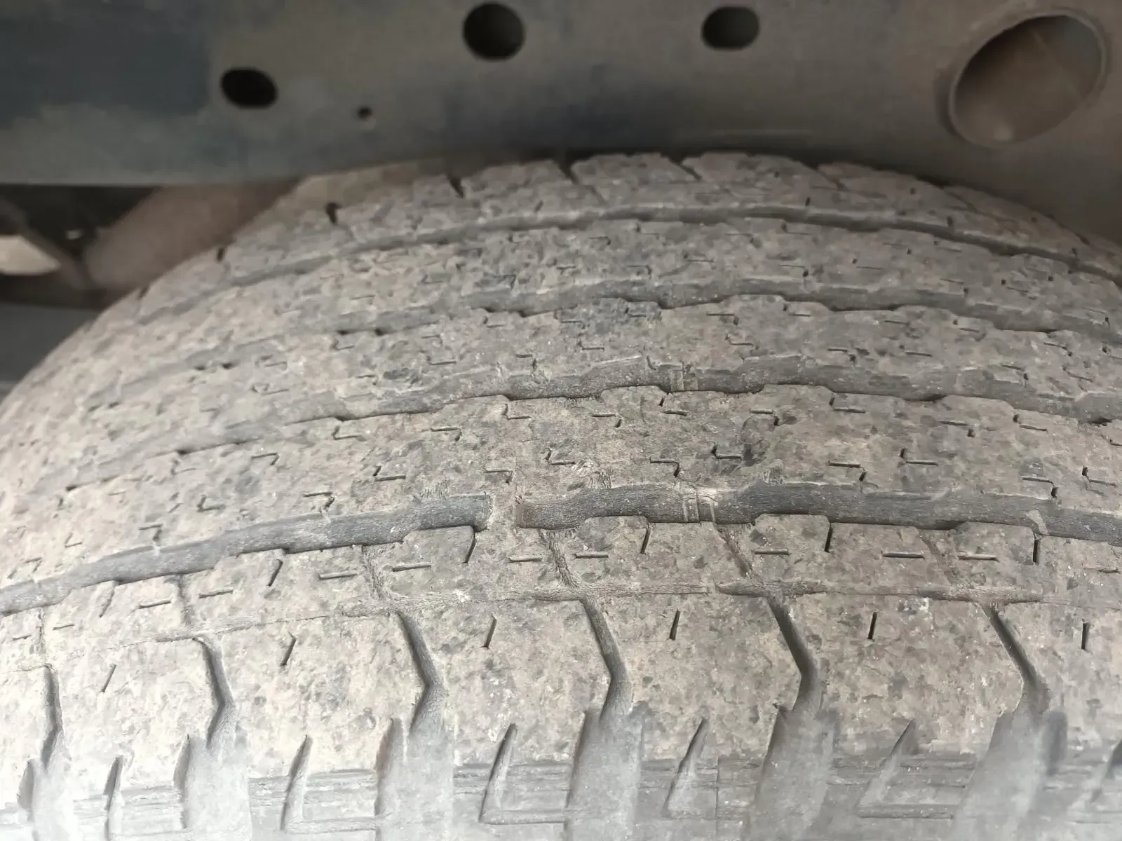 Close-up of a Worn Tyre Mounted Under a Vehicle, Showing Tread Pattern and Dirt — South West 4WD Wreckers In Brisbane, QLD
