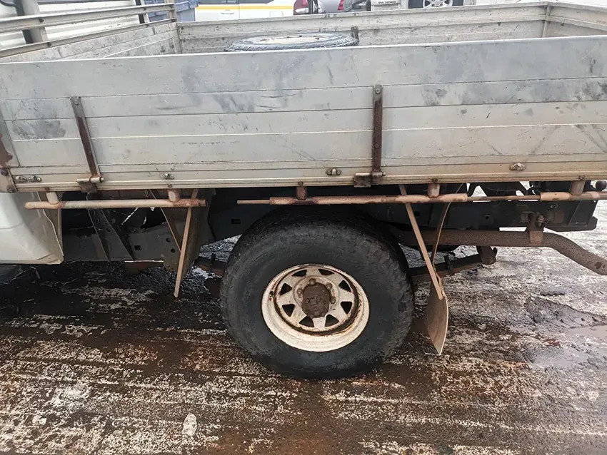 A Truck With a Flat Bed is Parked on a Dirt Road — South West 4WD Wreckers In Brisbane, QLD