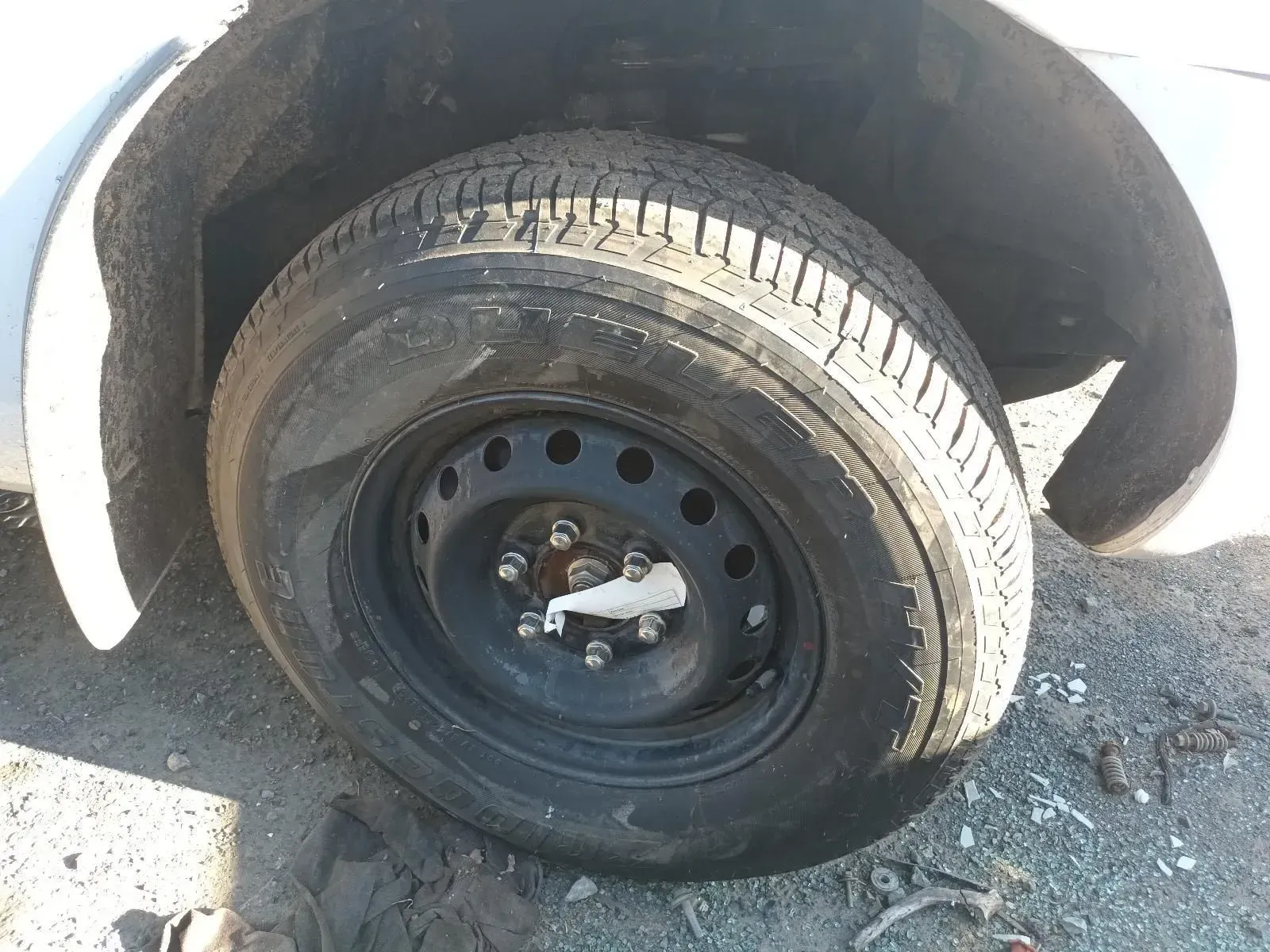 Black Car Tyre on a Black Rim, Slightly Deflated, Under a White Fender — South West 4WD Wreckers In Brisbane, QLD