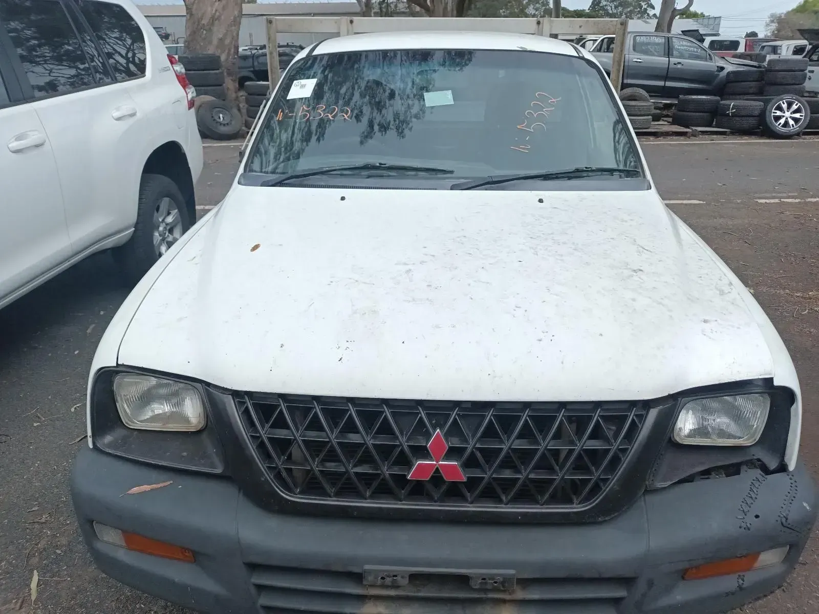 White Mitsubishi Triton Pickup Truck, Front View, in a Yard With Other Vehicles — South West 4WD Wreckers In Brisbane, QLD
