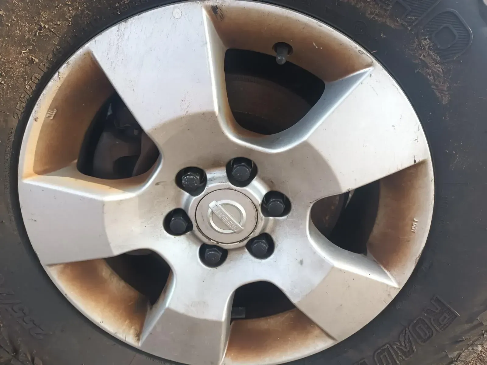 Silver Nissan Car Wheel With Six Lug Nuts, and a Muddy Tyre — South West 4WD Wreckers In Brisbane, QLD