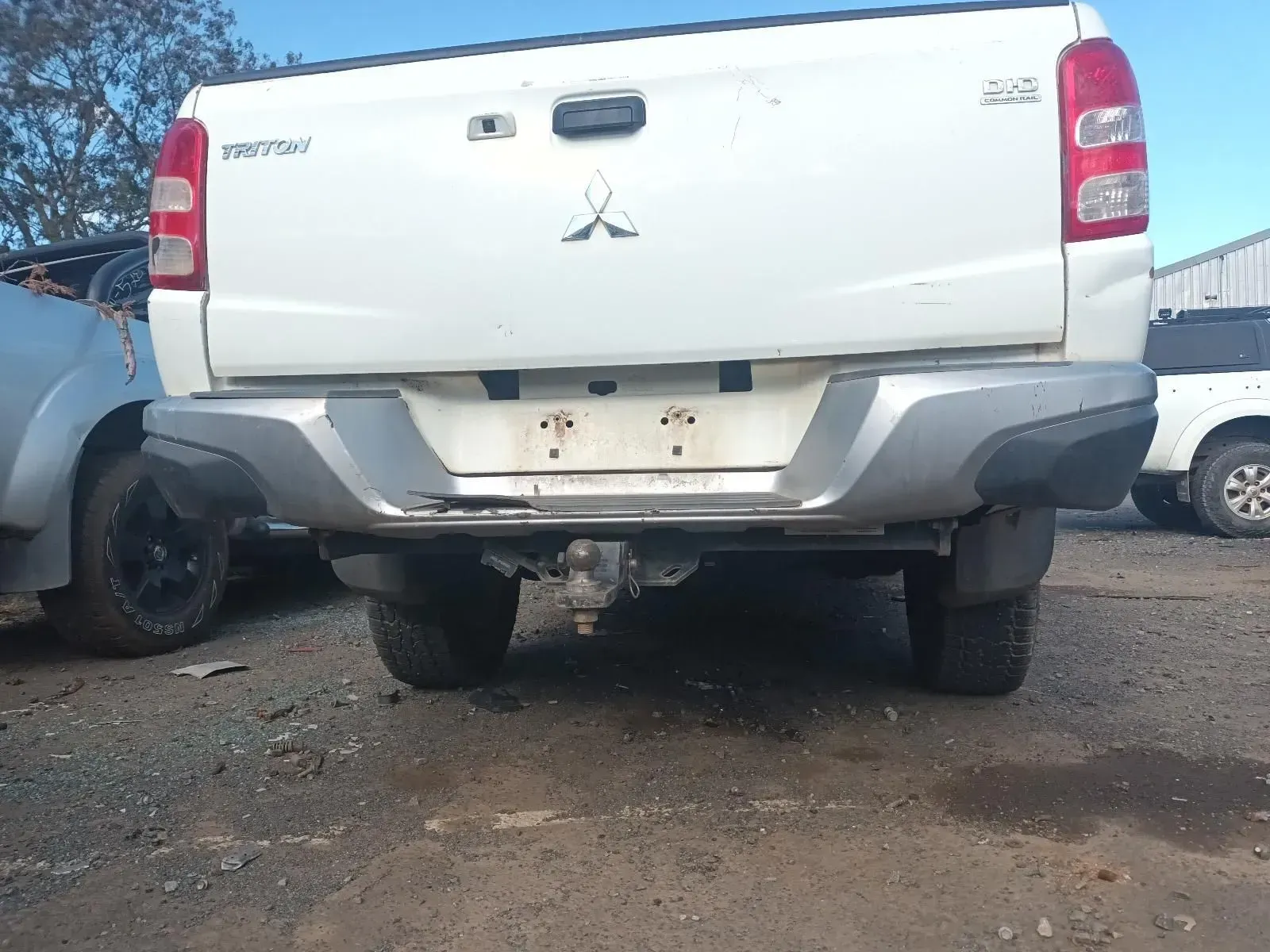 Rear View of a White Mitsubishi Triton Truck With a Tow Hitch in a Salvage Yard — South West 4WD Wreckers In Brisbane, QLD