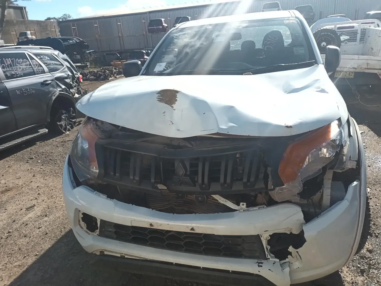 Damaged White Truck With Crumpled Hood and Broken Grill in a Salvage Yard — South West 4WD Wreckers In Brisbane, QLD