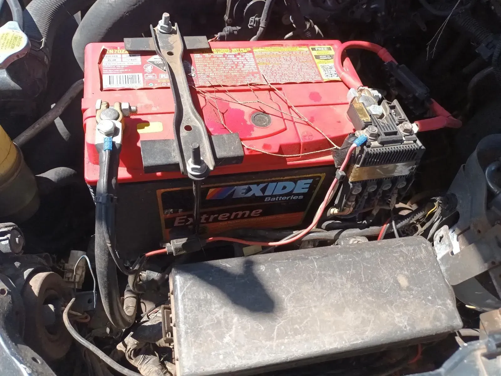 Red Car Battery in Engine Bay With Attached Cables and Fuse Box — South West 4WD Wreckers In Brisbane, QLD