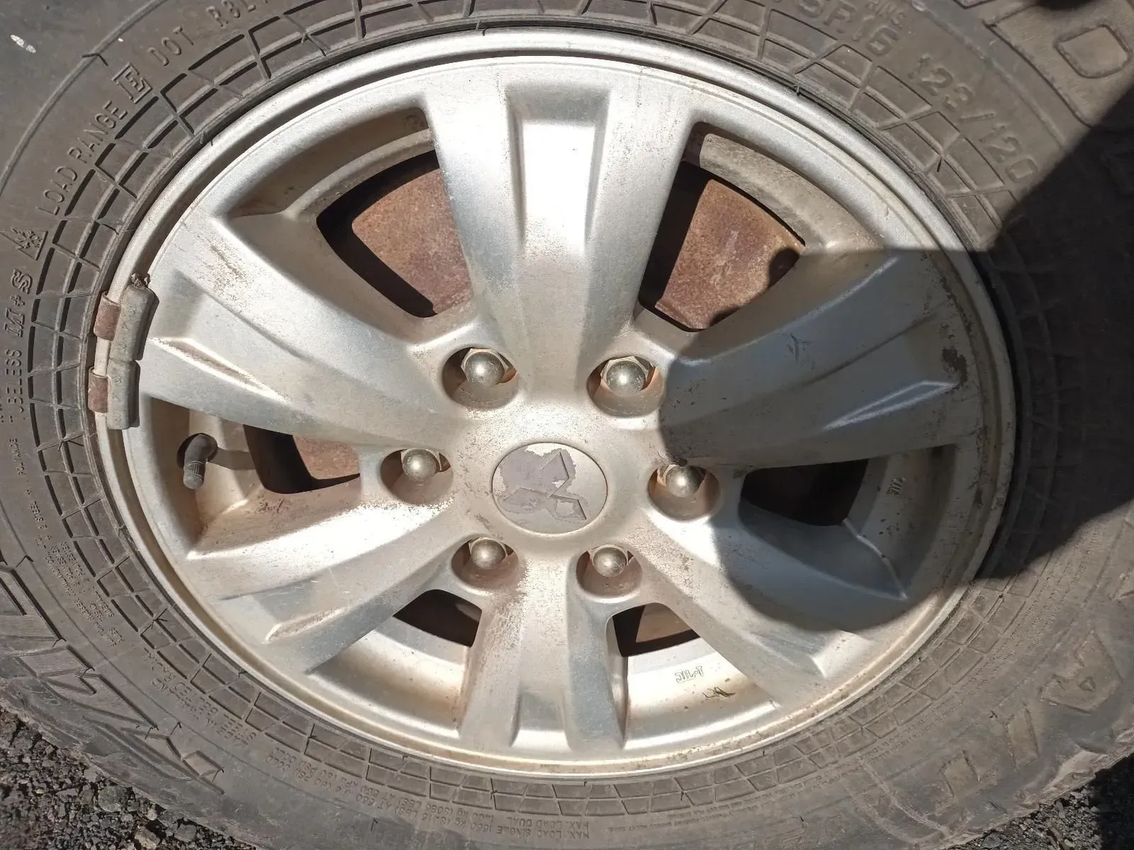 A Car Tyre and Wheel, Silver Hubcap, Dirty, With Visible Bolts and Tyre Tread — South West 4WD Wreckers In Brisbane, QLD